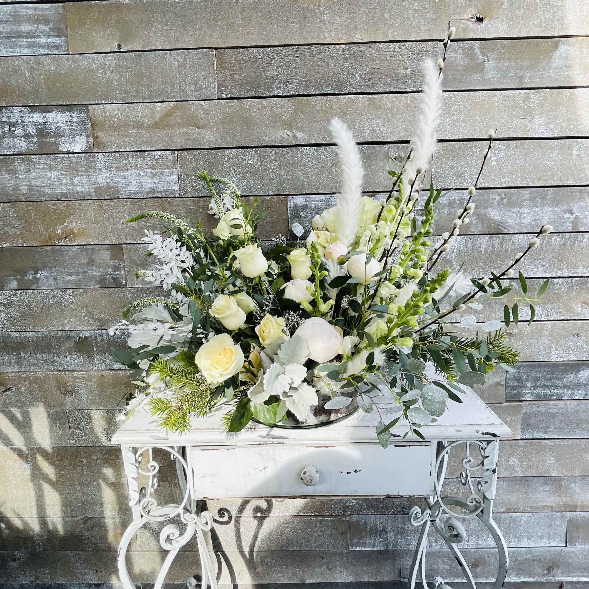 White rose arrangement with tall feathery accents in a white vase
