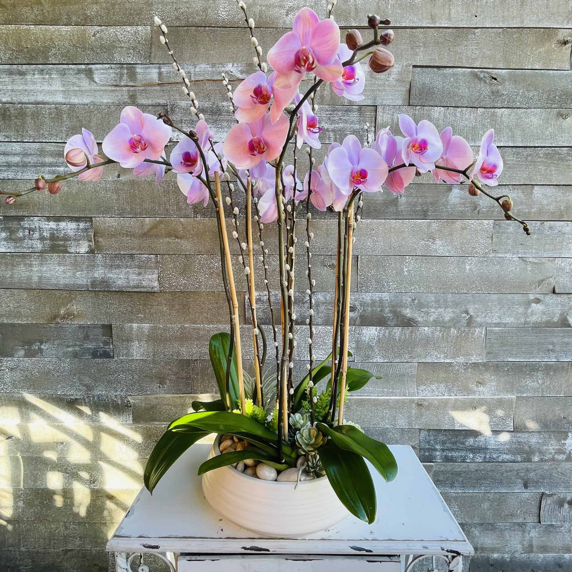Pink orchid arrangement in a white bowl planter