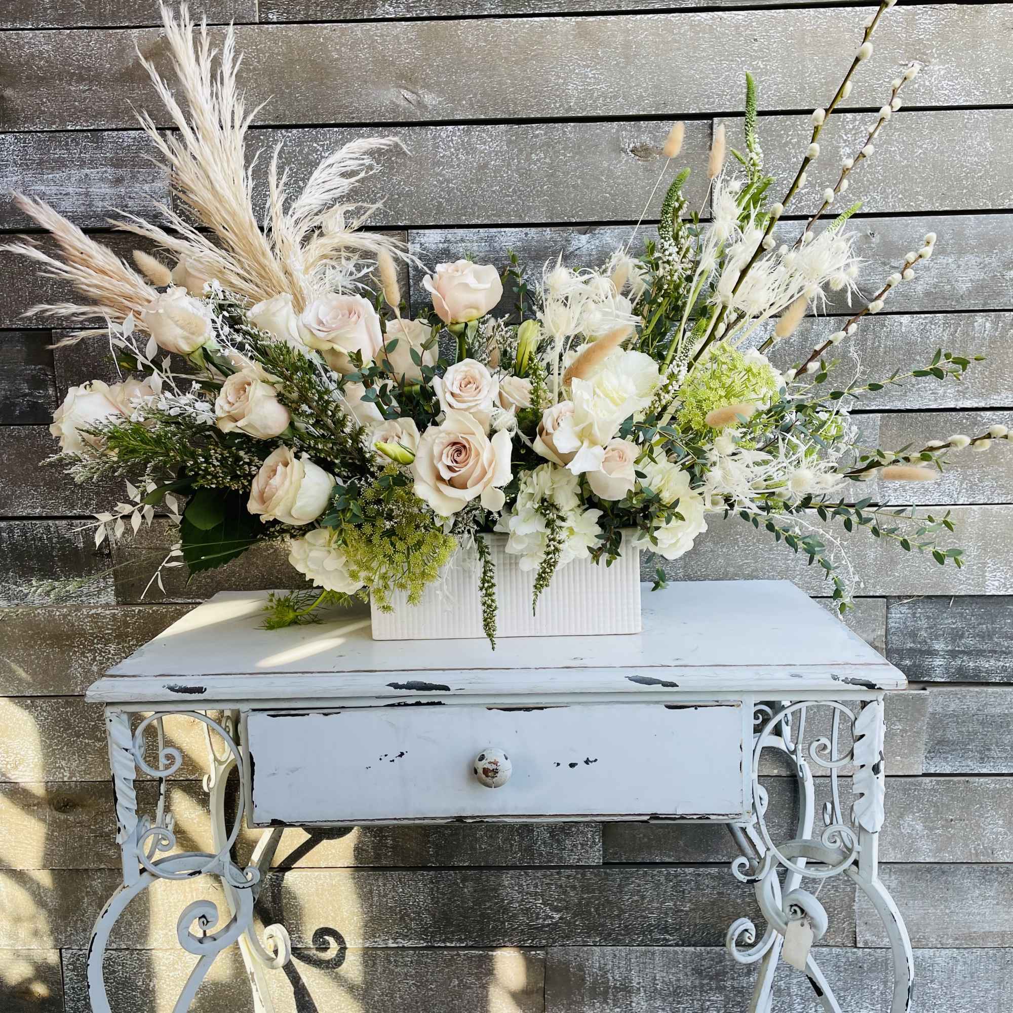 Large pale rose arrangement in a white rectangular container