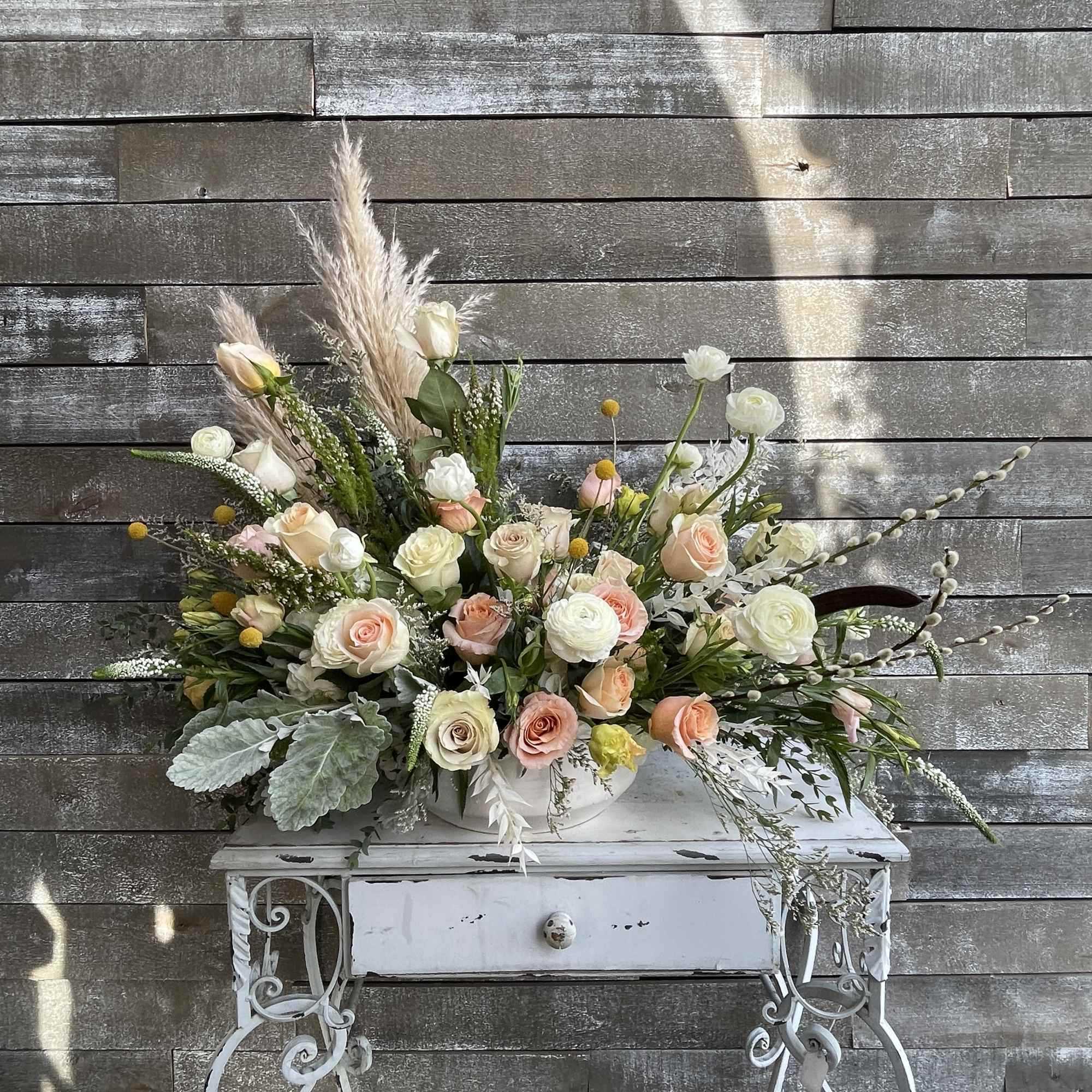Large pastel floral arrangement in a white container on a decorative table, photo 3 of 6