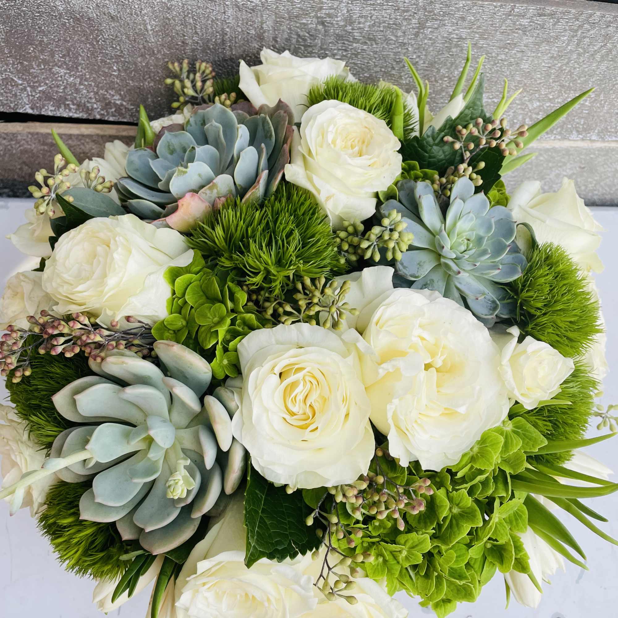 Bouquet of white roses and blue-green succulents with bright green accents