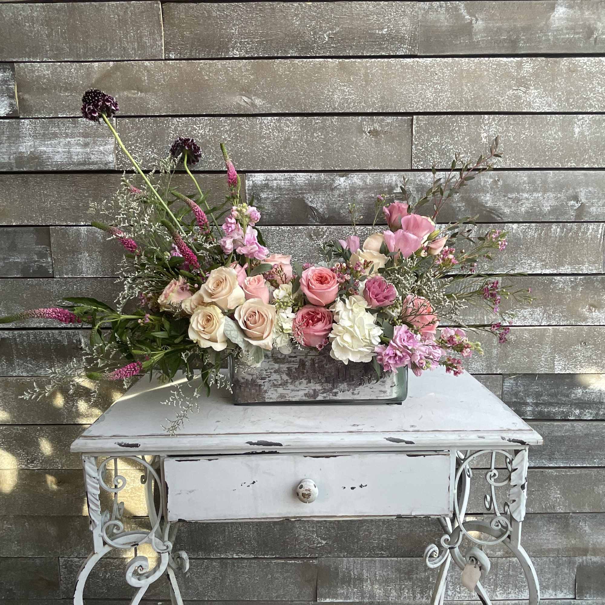 Low floral arrangement of pink and cream roses in a rectangular container