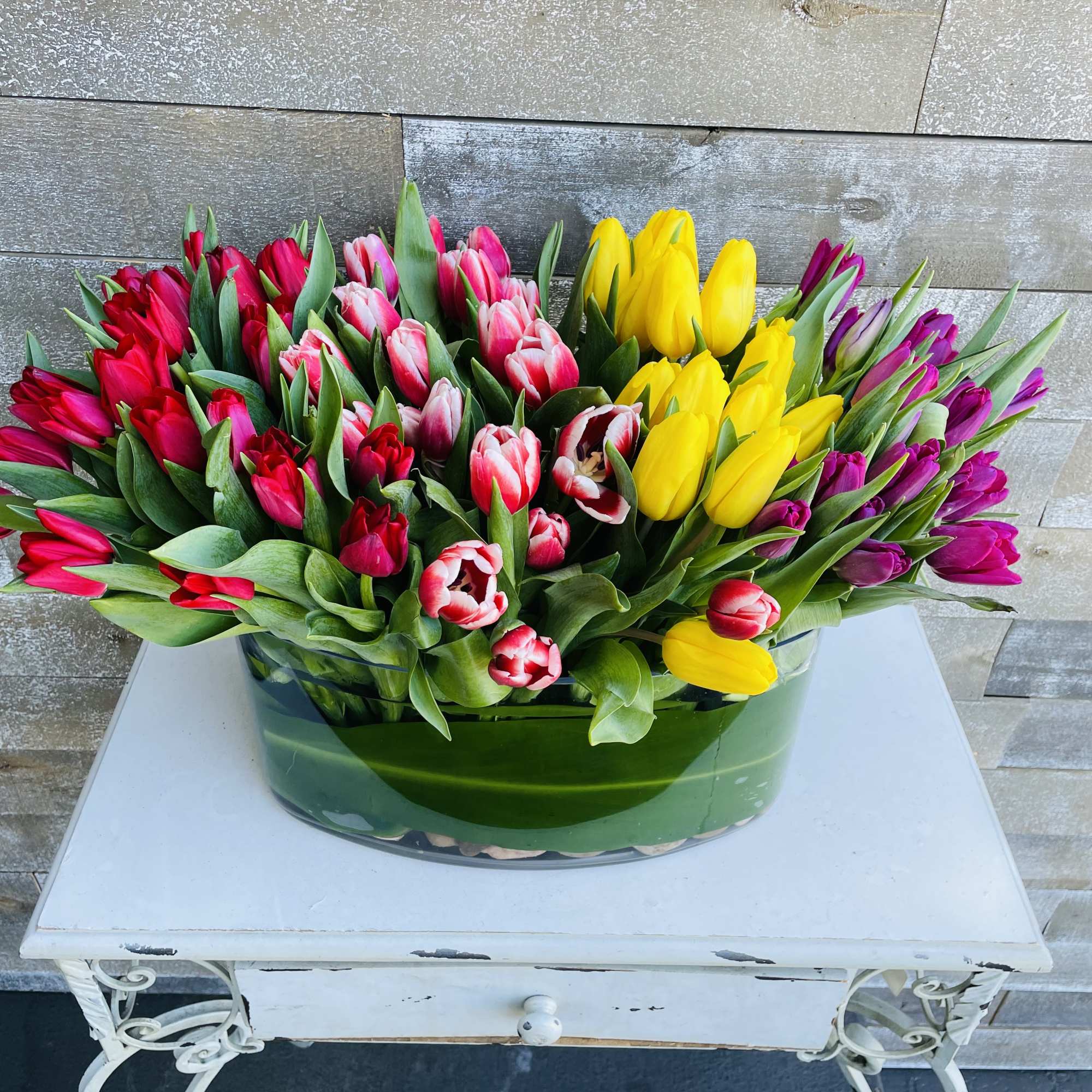 Colorful tulip arrangement in a low glass vase