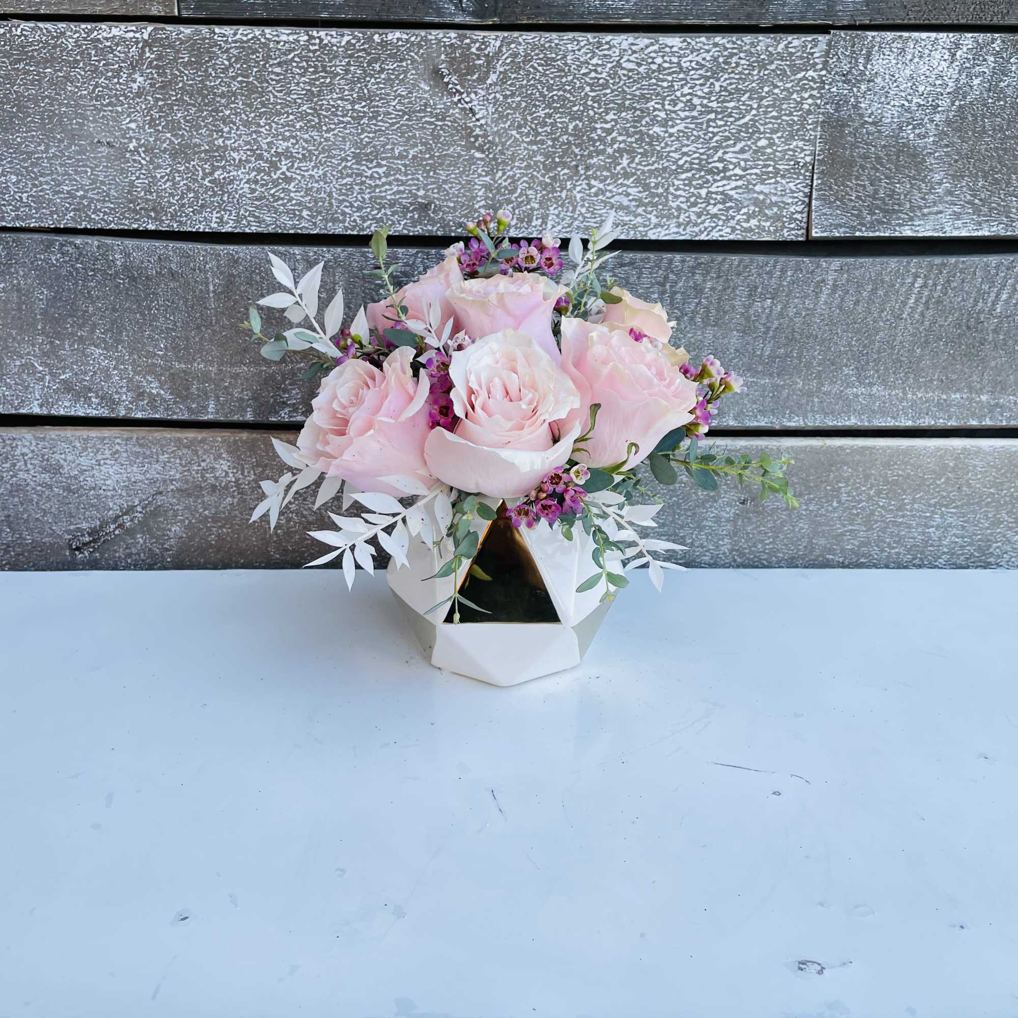 Pink roses in a white geometric vase with small filler flowers