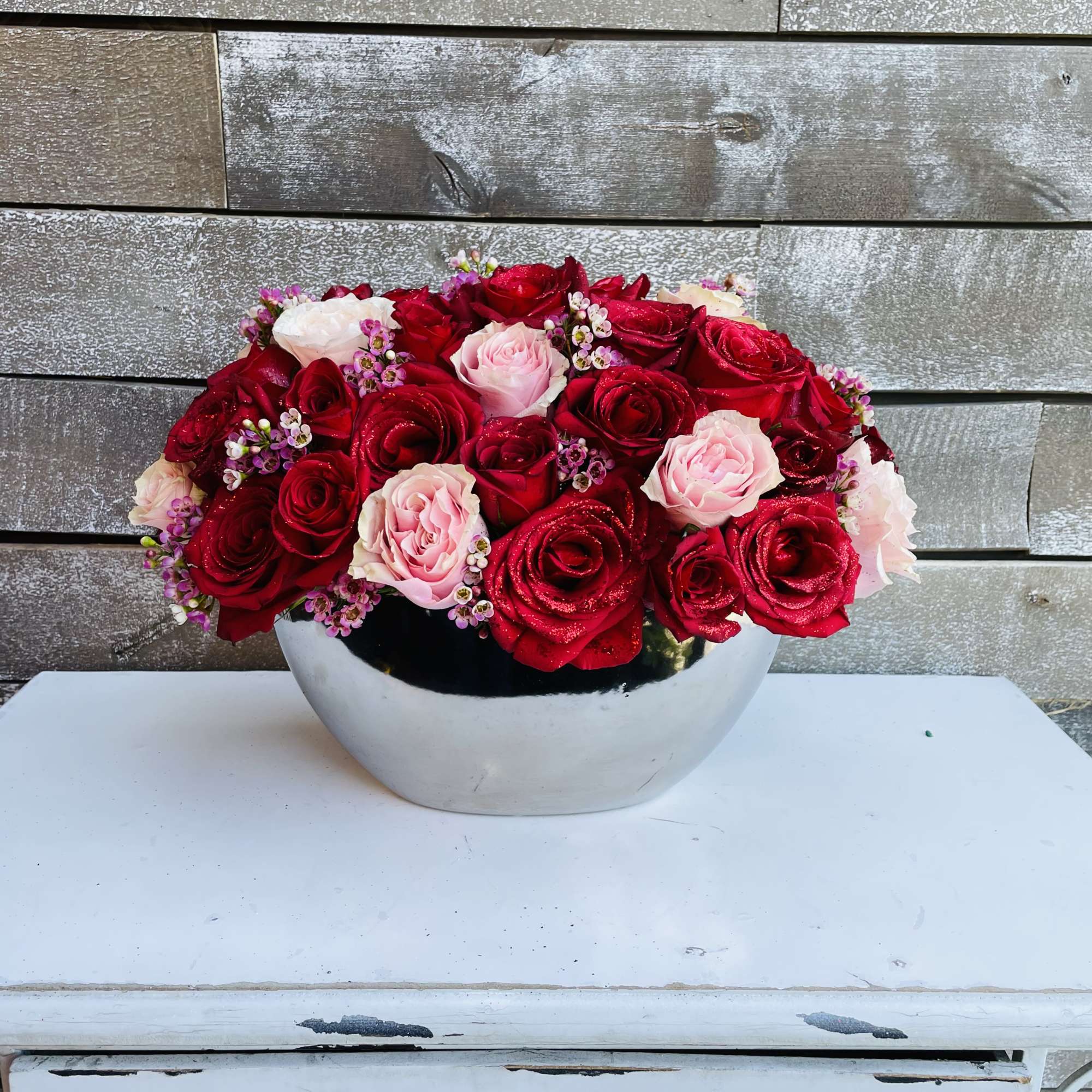 Red and pink roses arranged in a white bowl vase