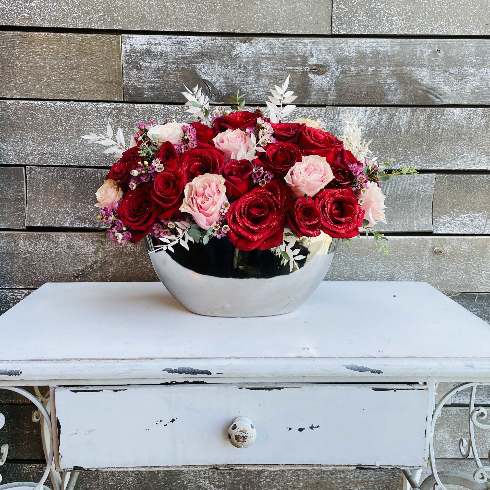 Red and pink roses arranged in a silver bowl vase