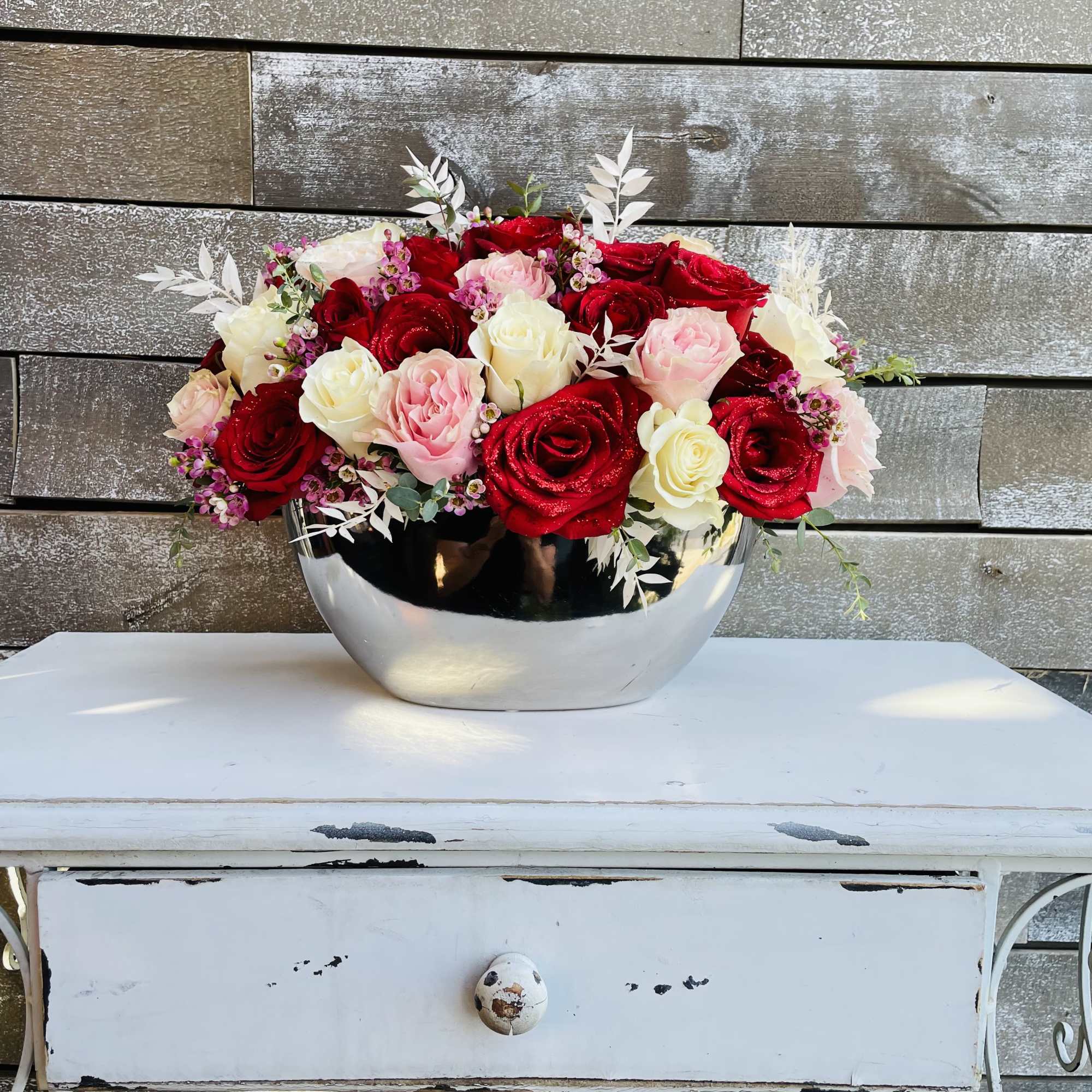 Red, pink, and white roses arranged in a silver bowl