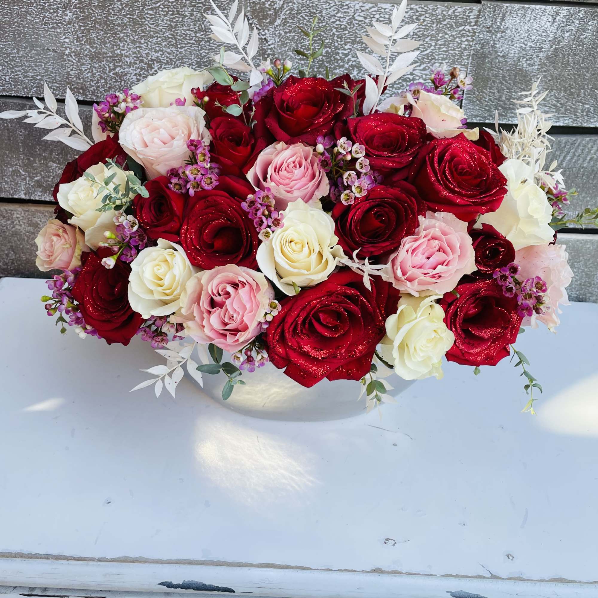 Bouquet of red, pink, and white roses in a white container