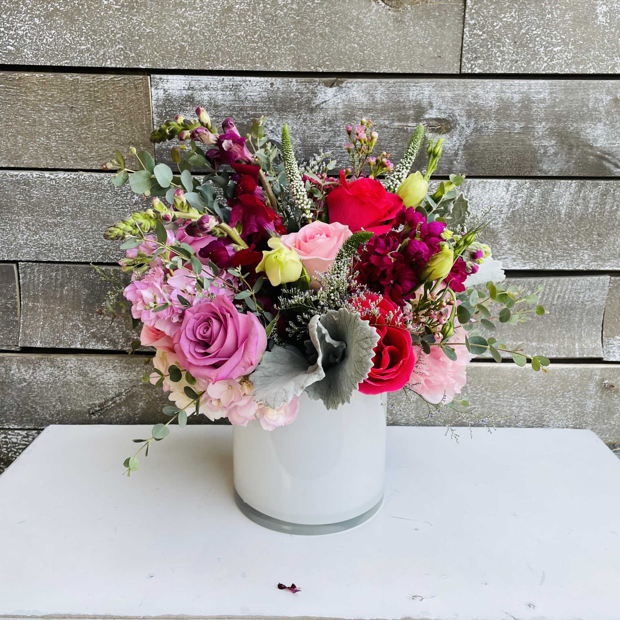 Mixed bouquet of pink and red flowers in a white vase
