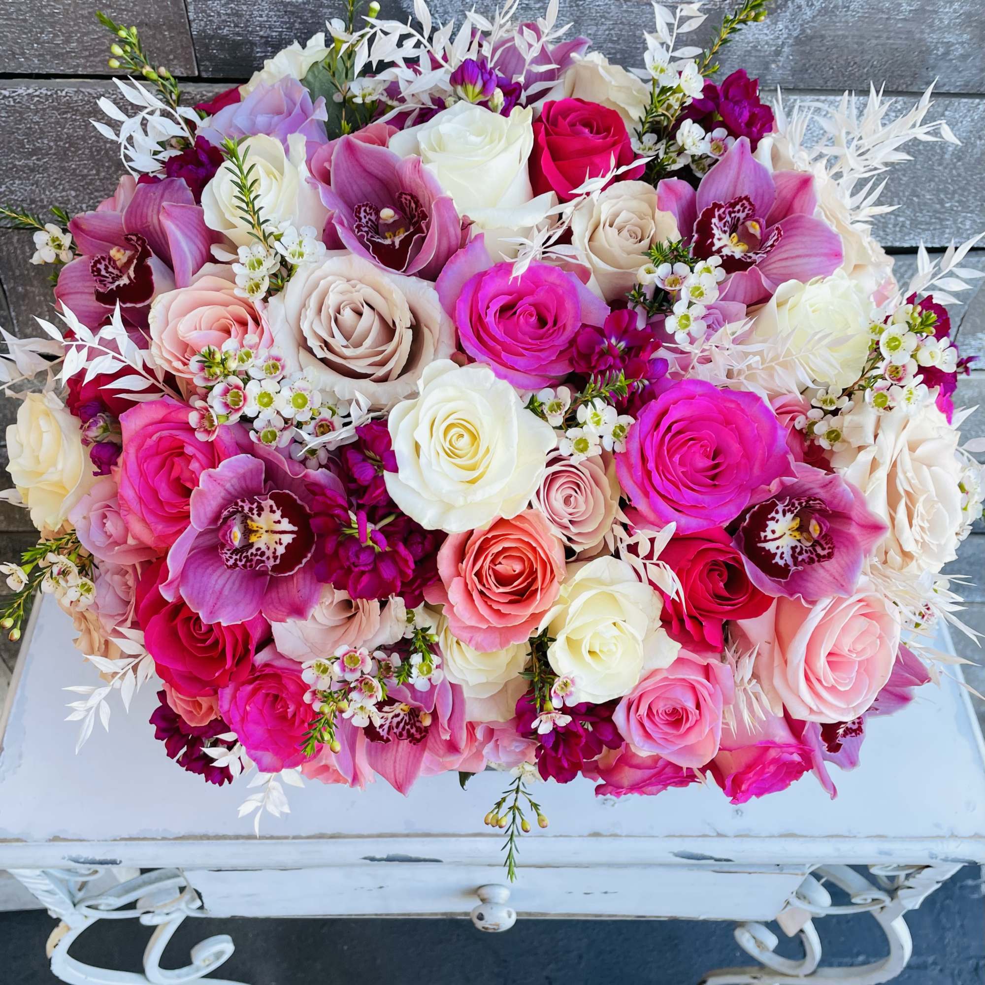 Bouquet of pink, white, and cream roses with orchids and small white filler flowers