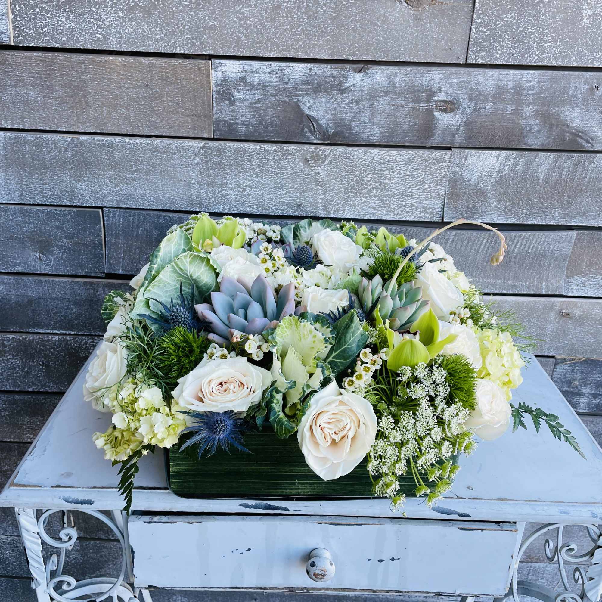 Low floral arrangement with white roses and succulents in a rectangular container