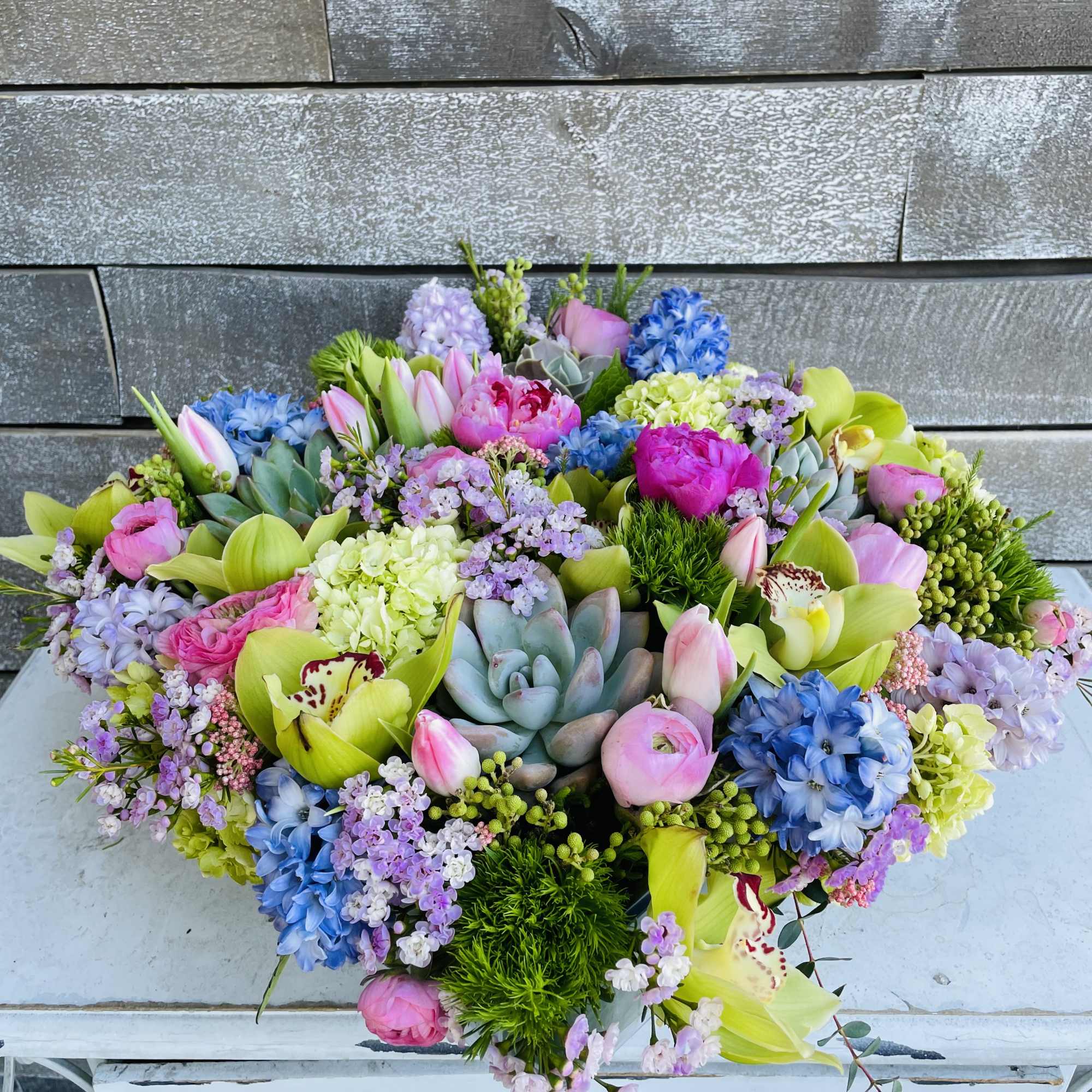 Colorful mixed bouquet with succulents, orchids, tulips, and hydrangeas