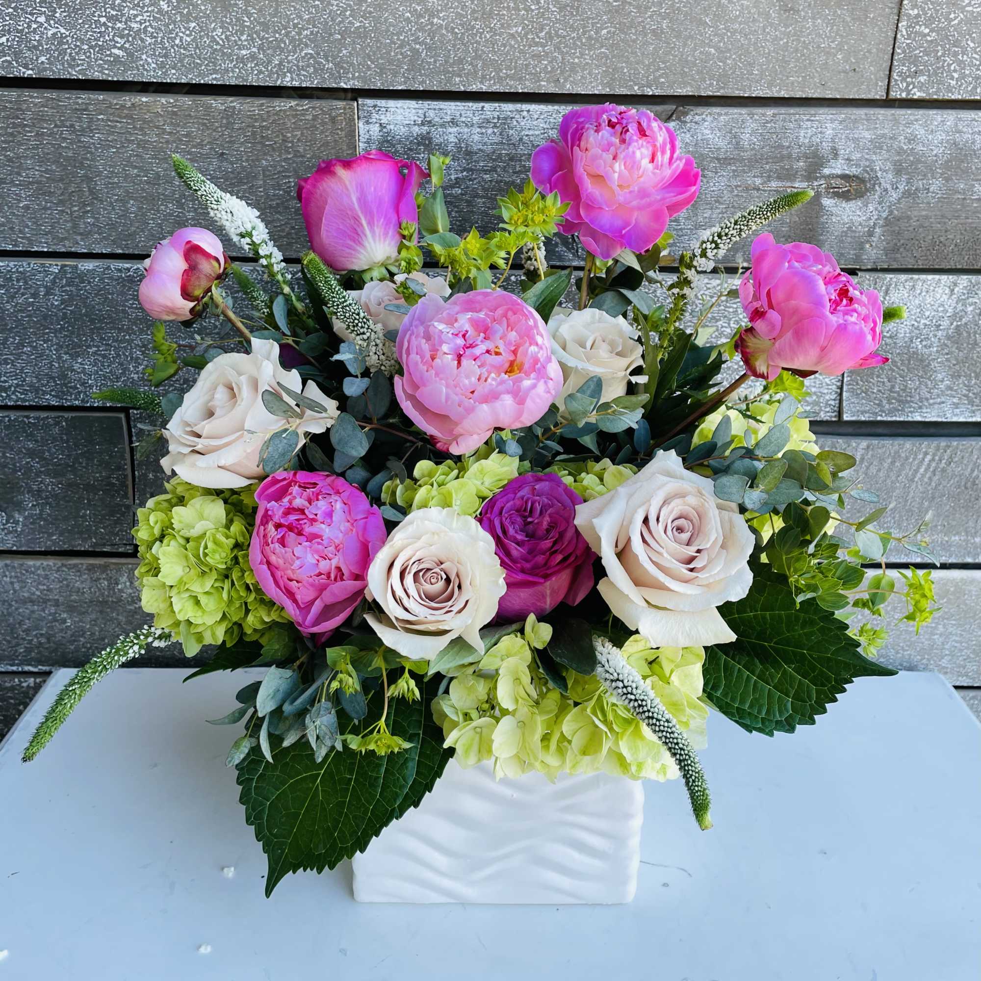 Pink peonies and pale roses arranged in a white vase