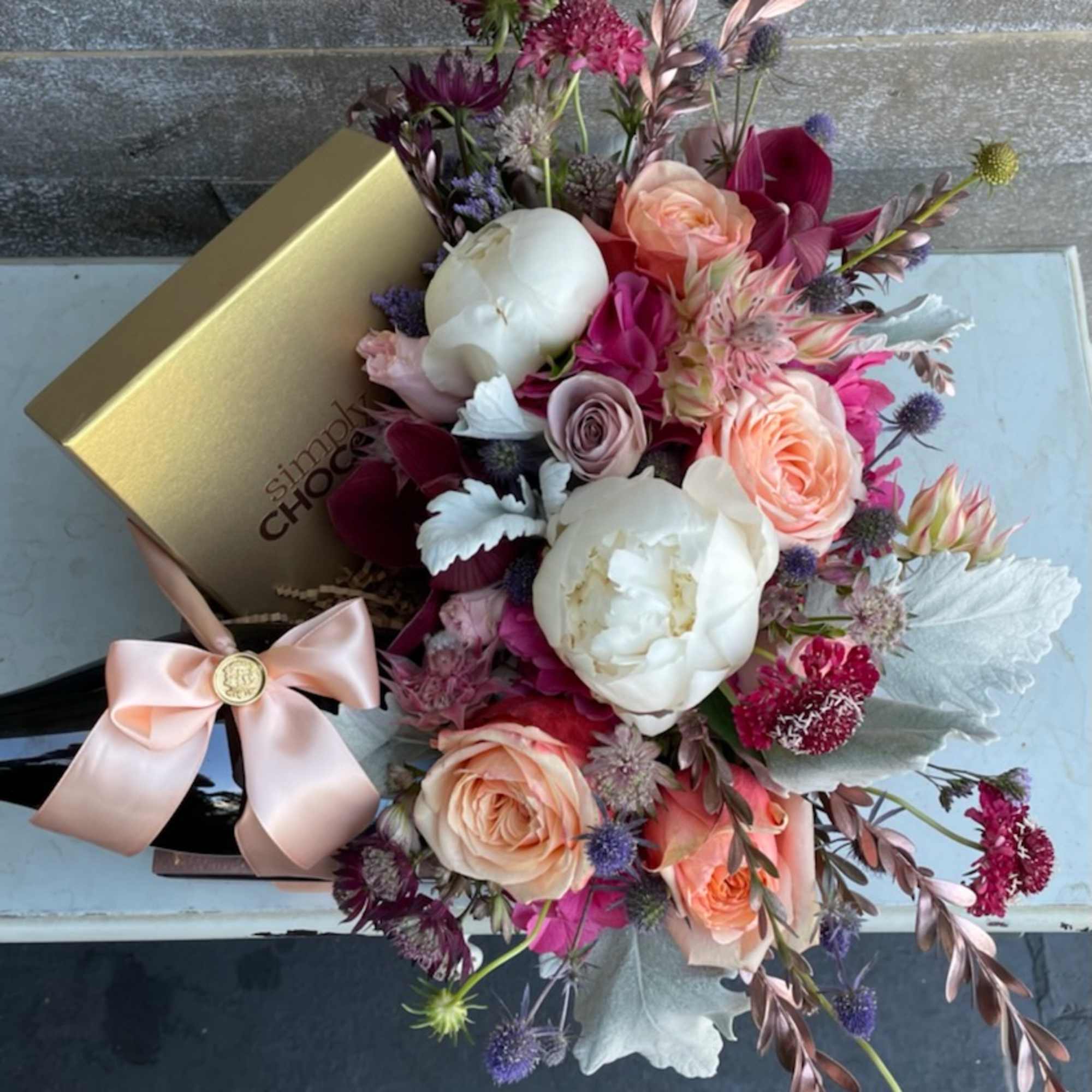 Mixed bouquet with peach and white roses in a gift box tied with a pink ribbon