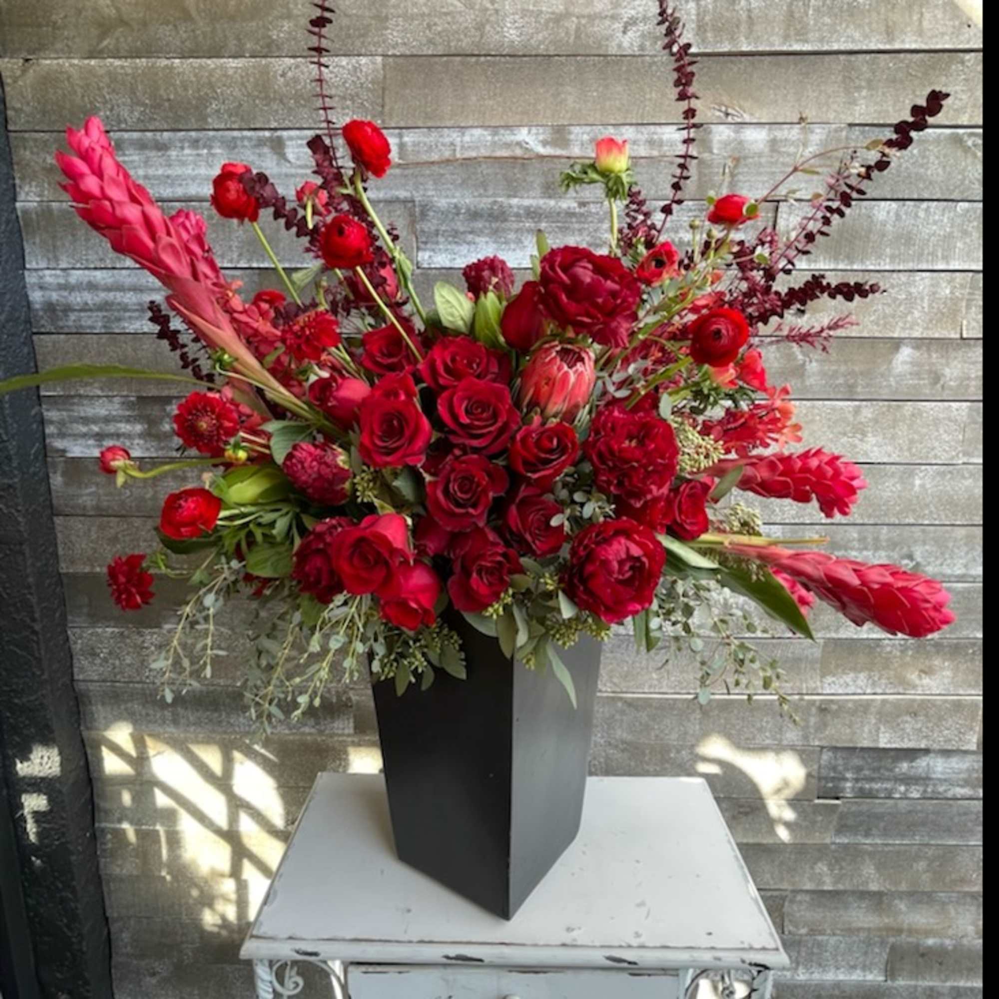 Red floral arrangement in a tall black vase