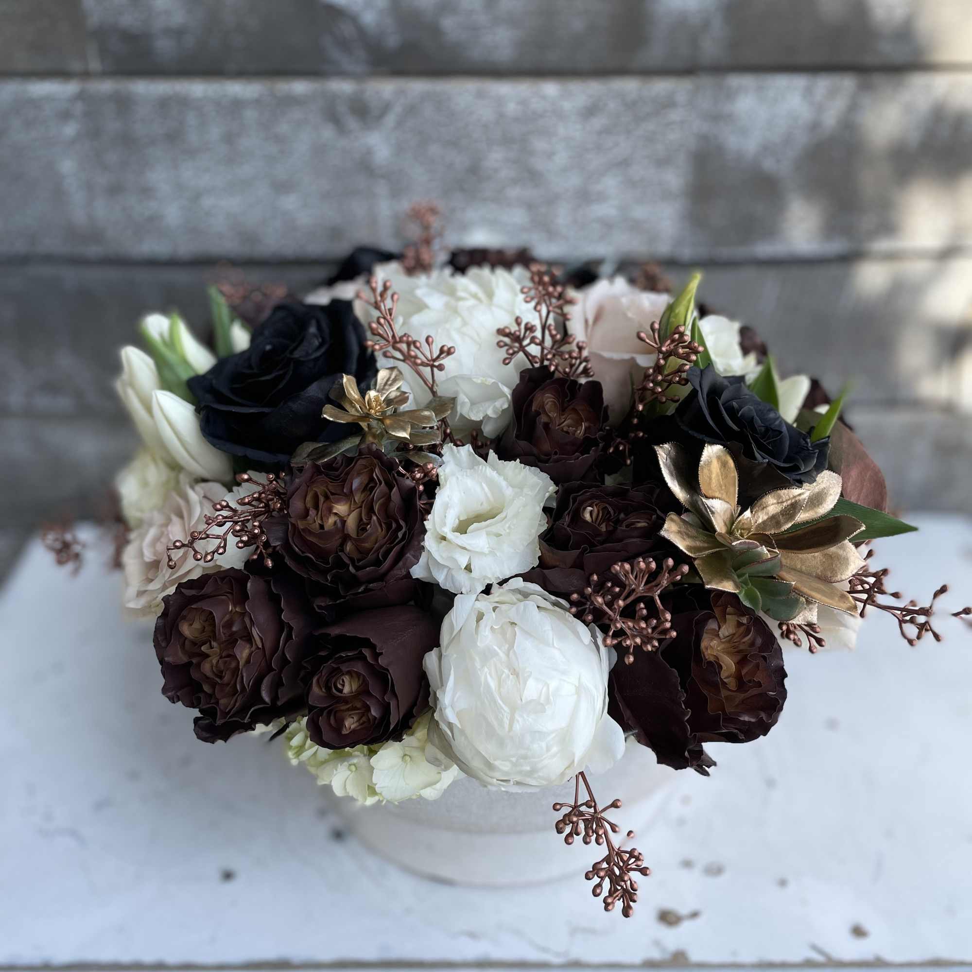 Bouquet of dark and white roses in a white container