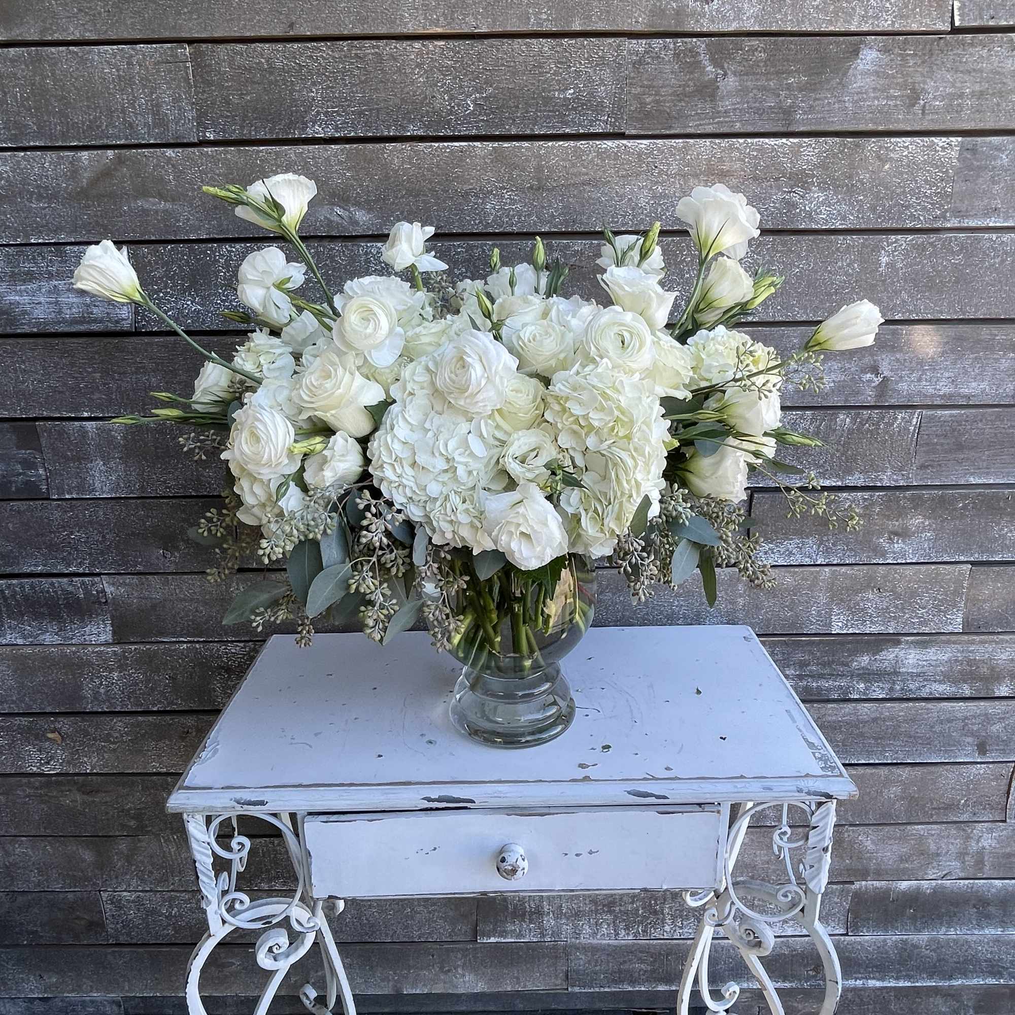 White floral arrangement in a glass vase on a small table