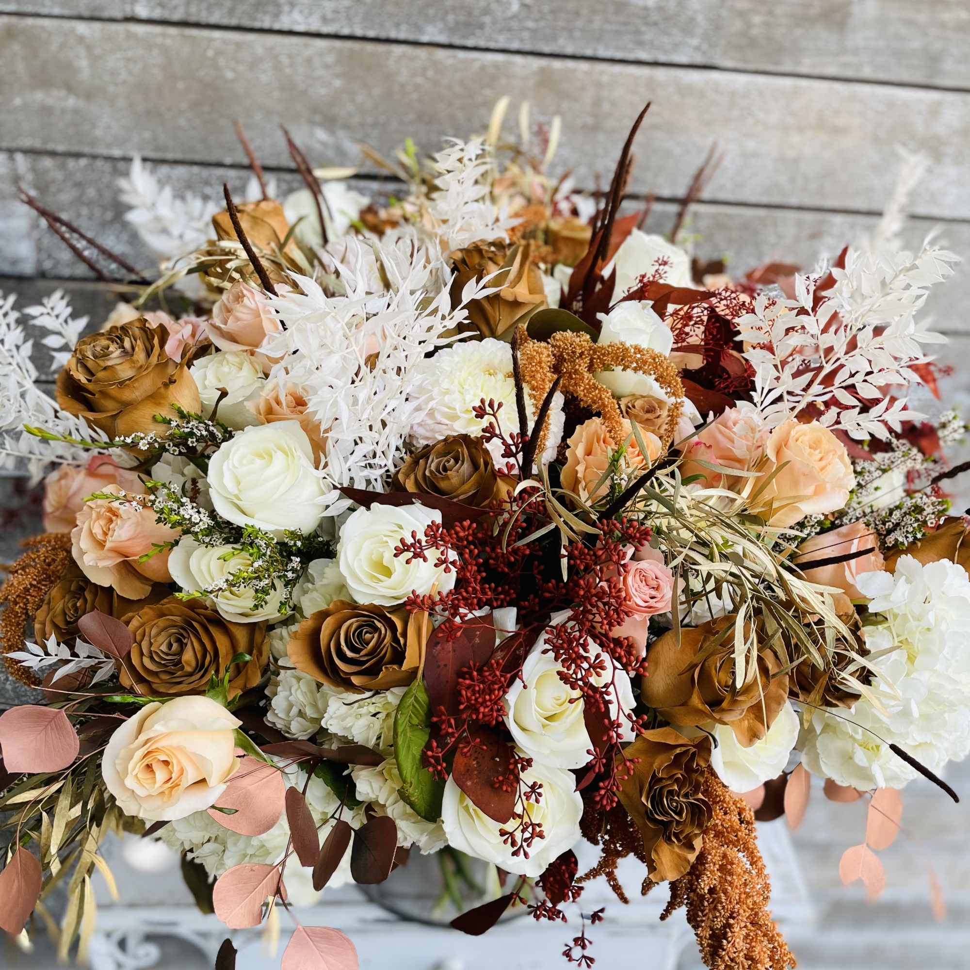 Bouquet of white, peach, and brown roses with dried accents