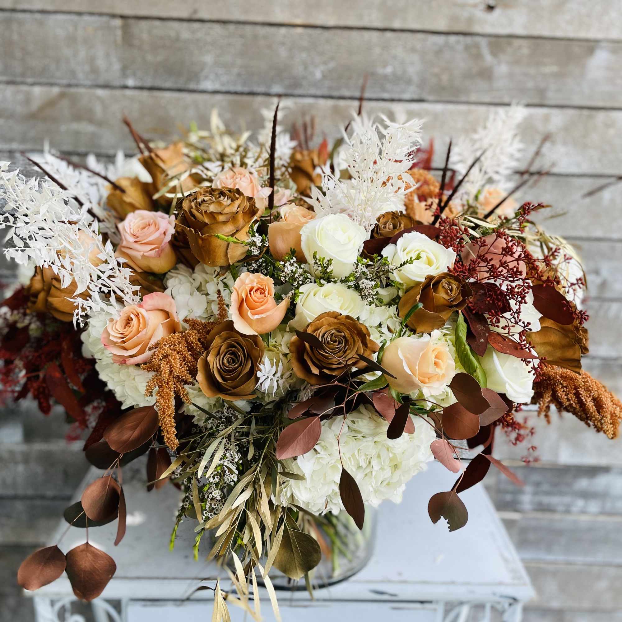 Bouquet of peach, white, and brown roses in a glass vase