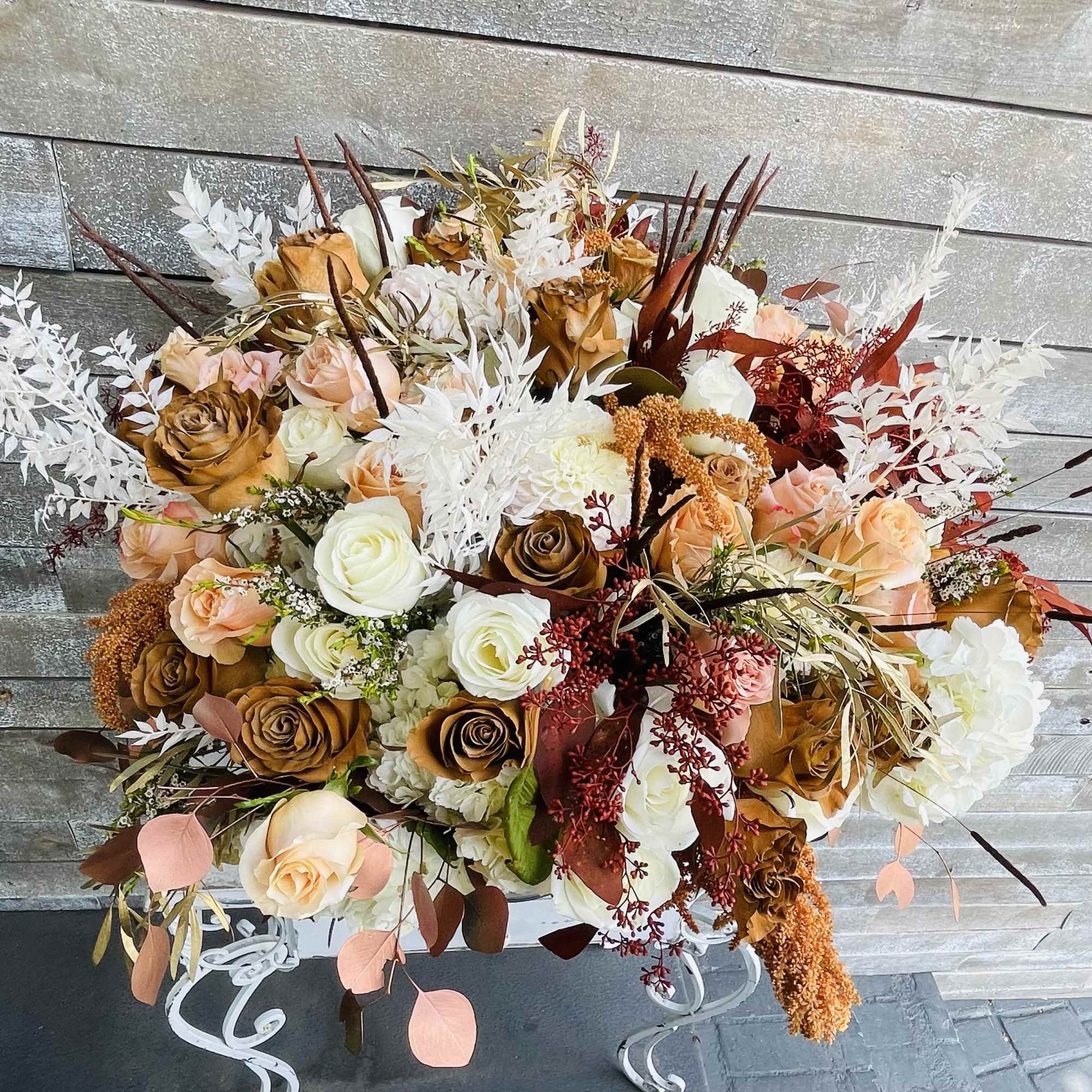 Large bouquet of peach, white, and brown roses with dried foliage