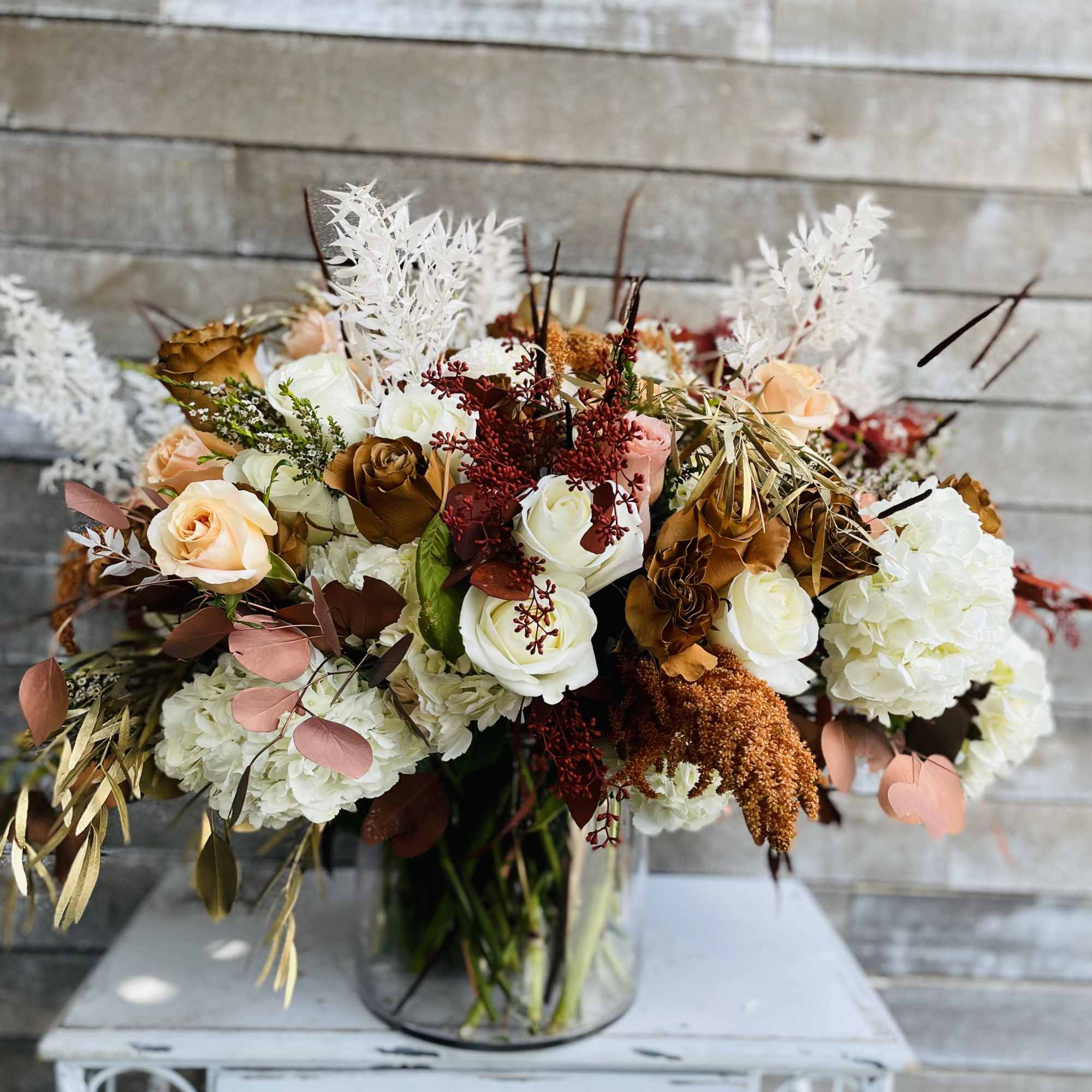 Bouquet of white, peach, and brown roses in a glass vase