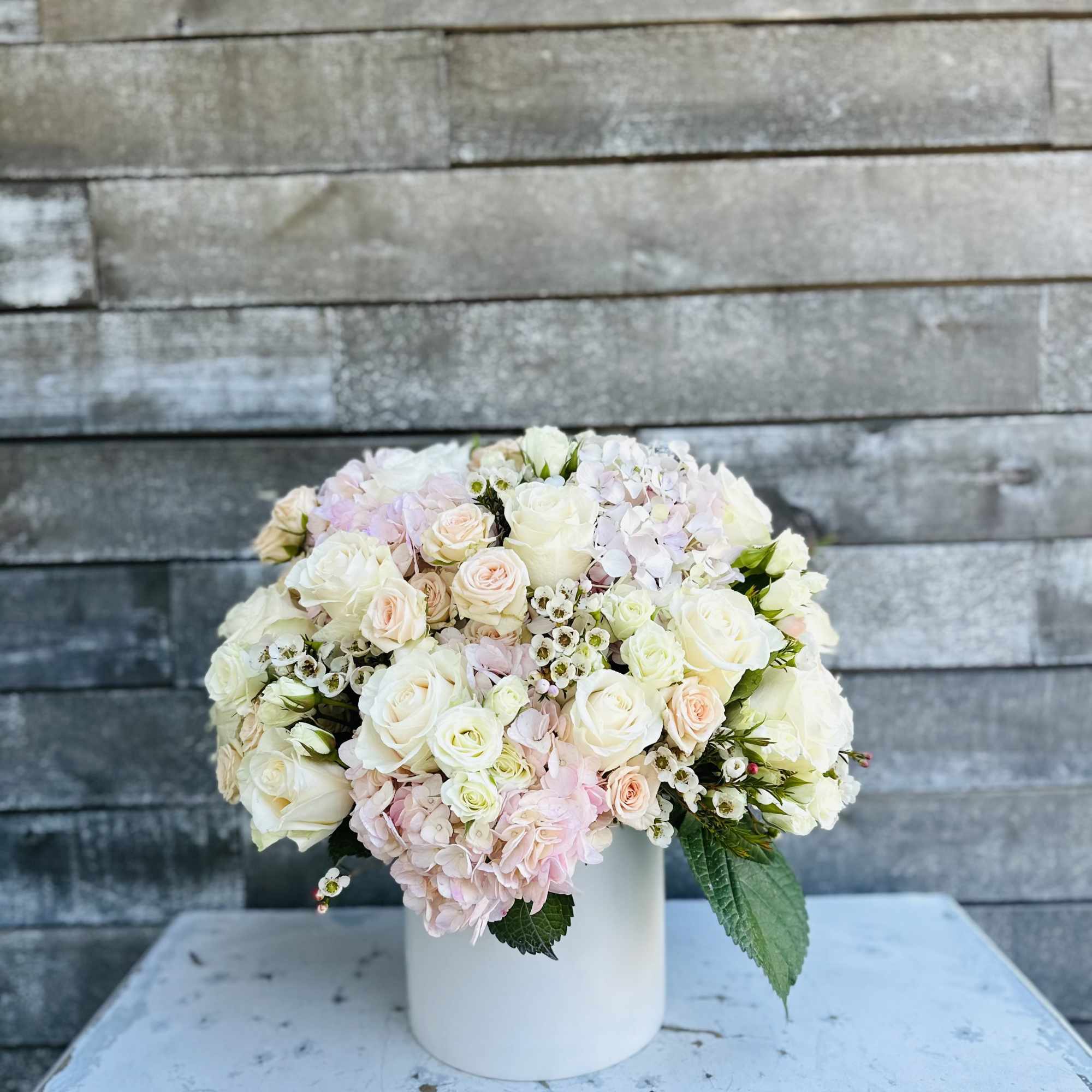 Round bouquet of white and blush roses in a white vase