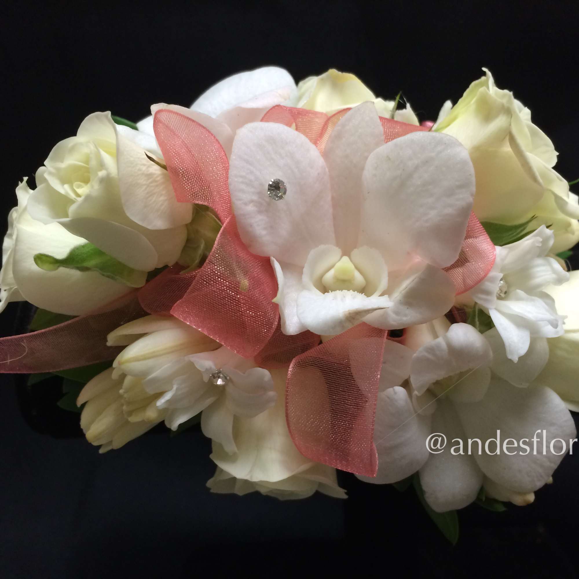 White rose and orchid bouquet with pink ribbon on a black background