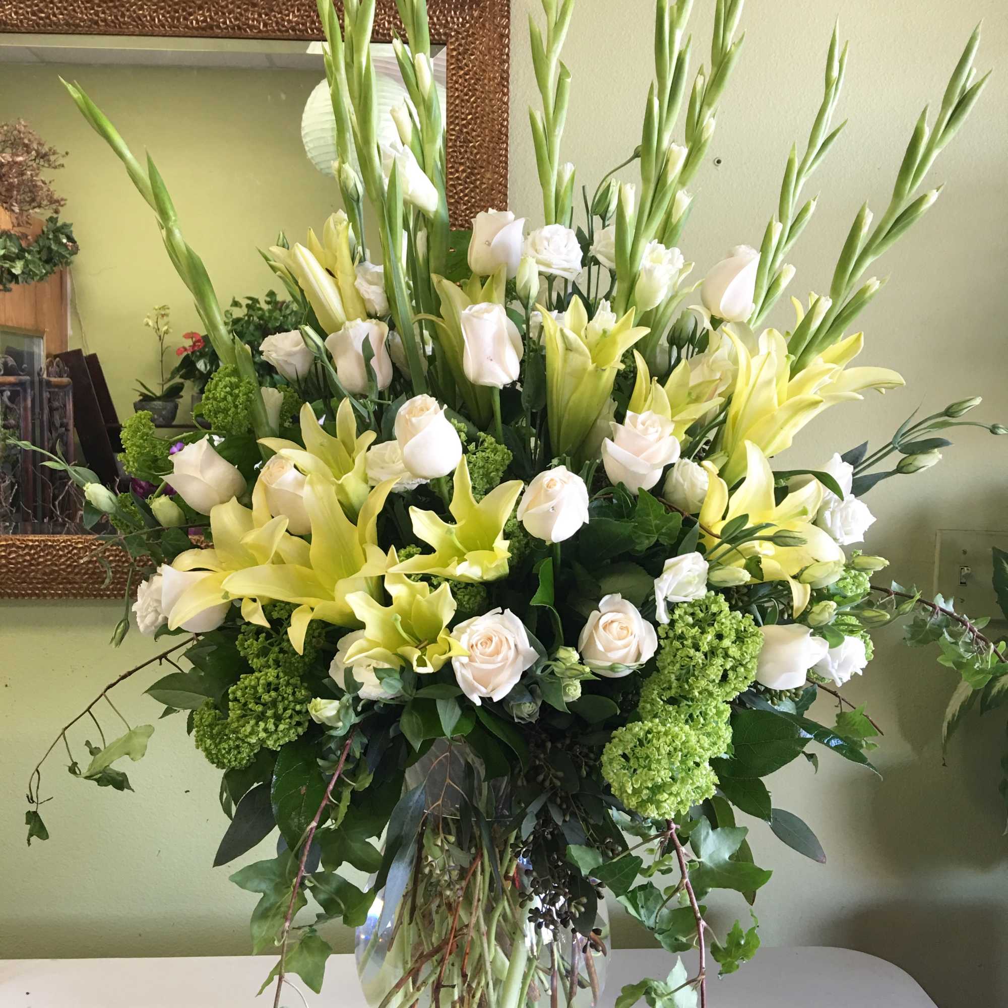 Tall bouquet of white roses and yellow lilies in a glass vase