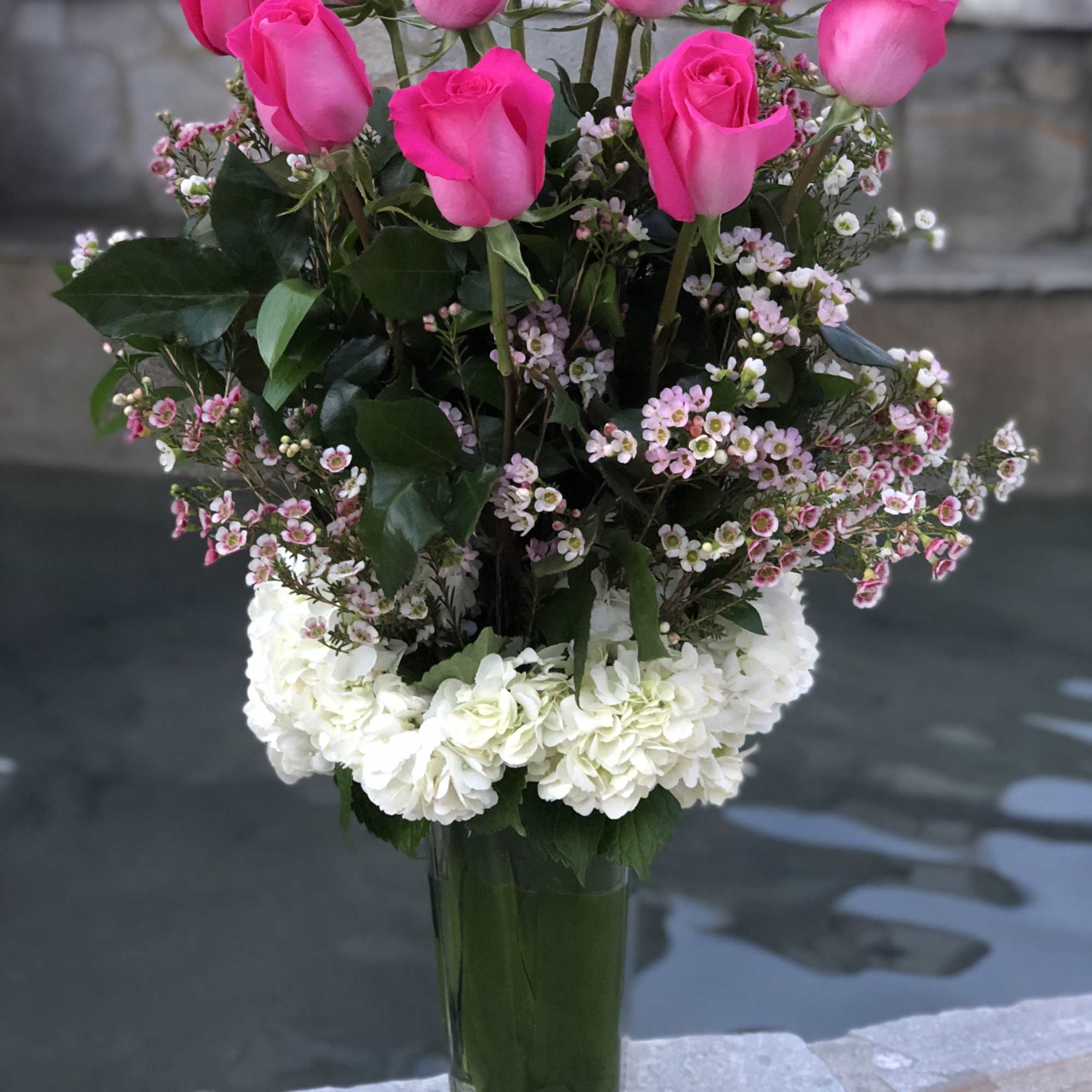 Pink roses and white hydrangeas in a tall glass vase