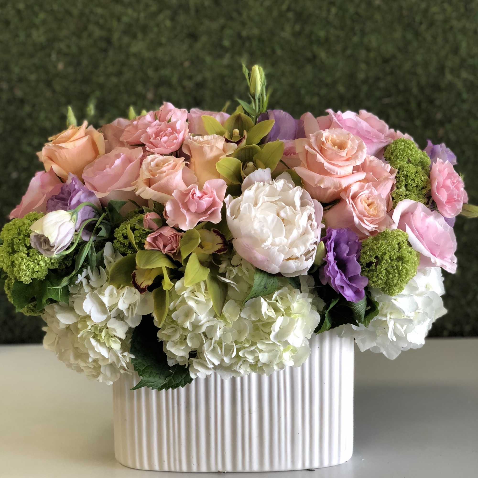 Pink and peach roses with white hydrangeas in a ribbed white vase