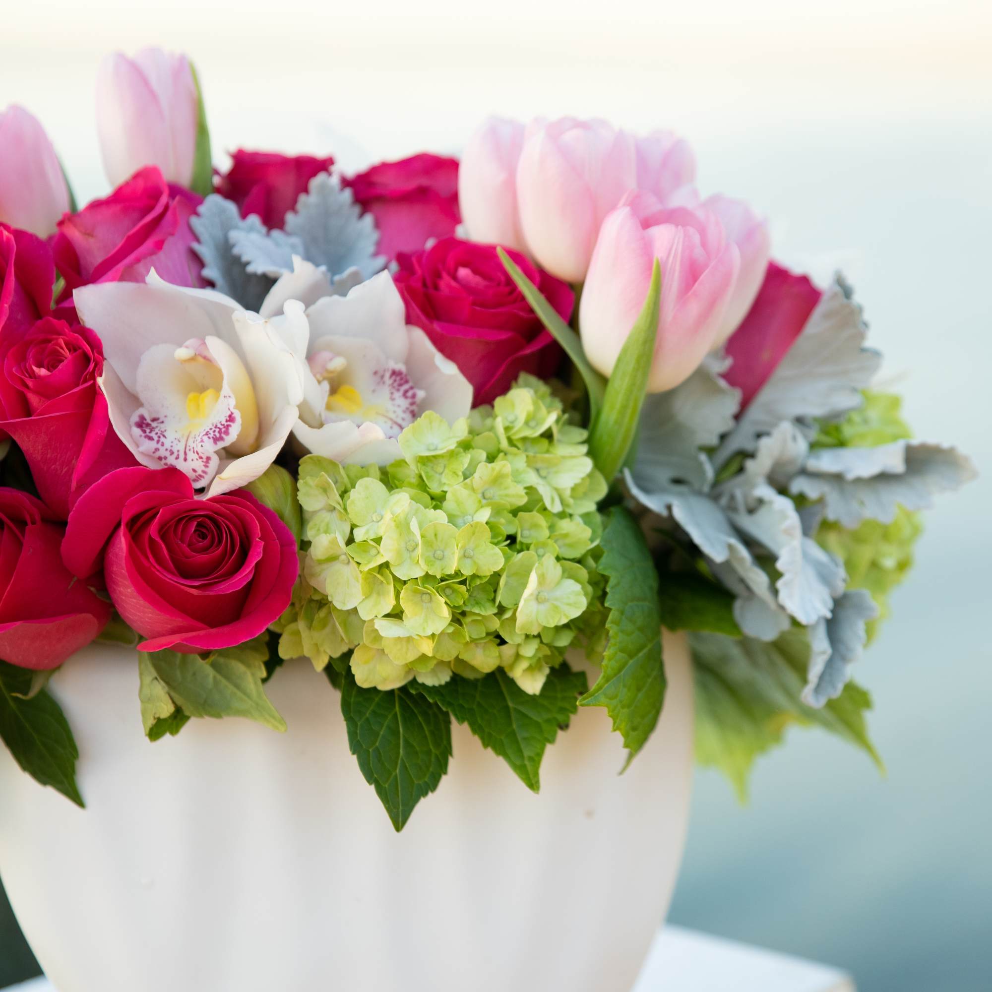 Pink roses and tulips in a white vase with pale hydrangeas
