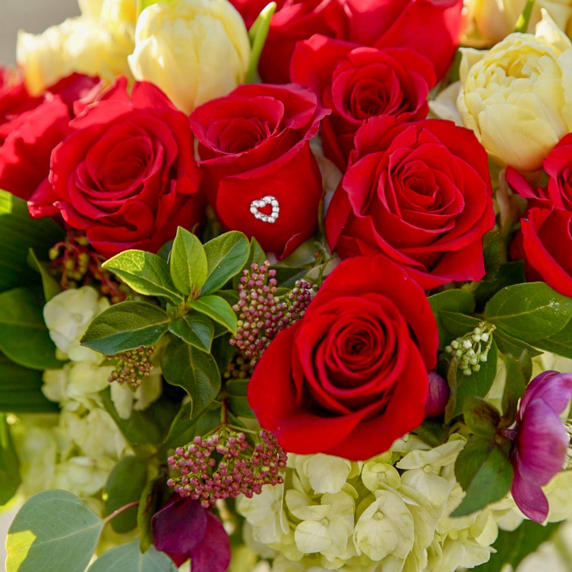 Bouquet of red roses and pale cream flowers with greenery
