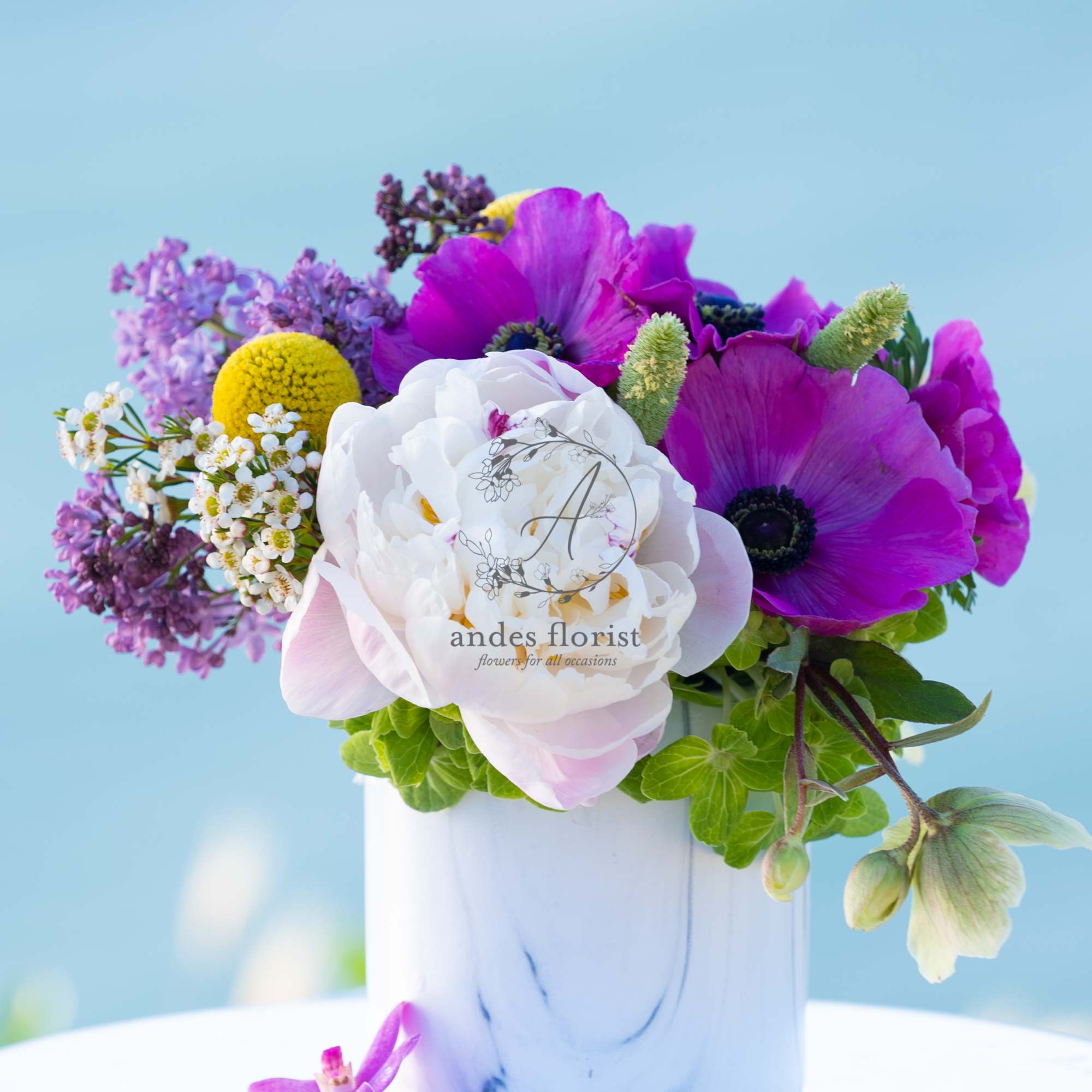 Purple and white flowers arranged in a white vase