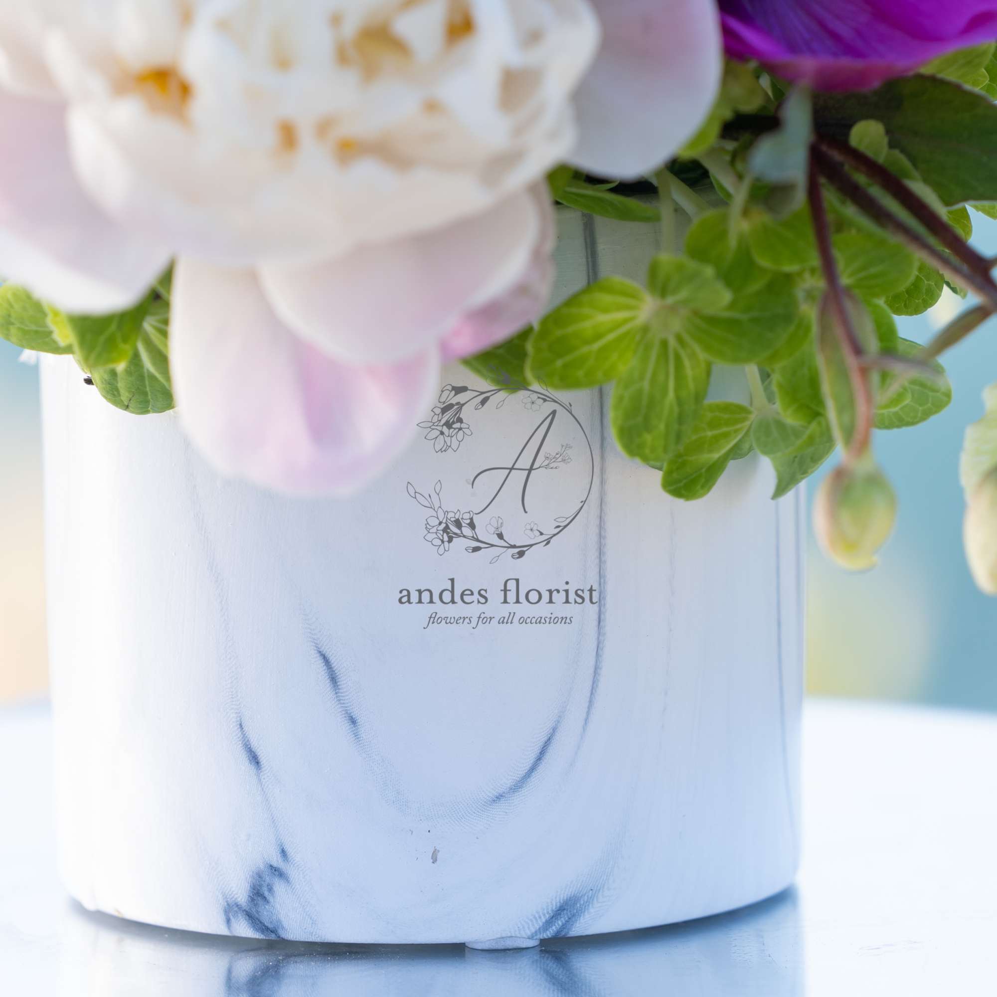 Soft pink and white flowers in a white marbled vase