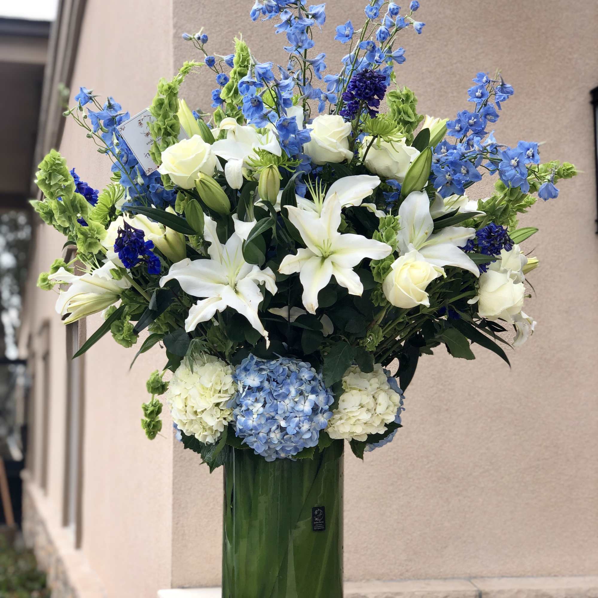 Tall blue and white floral arrangement in a glass vase