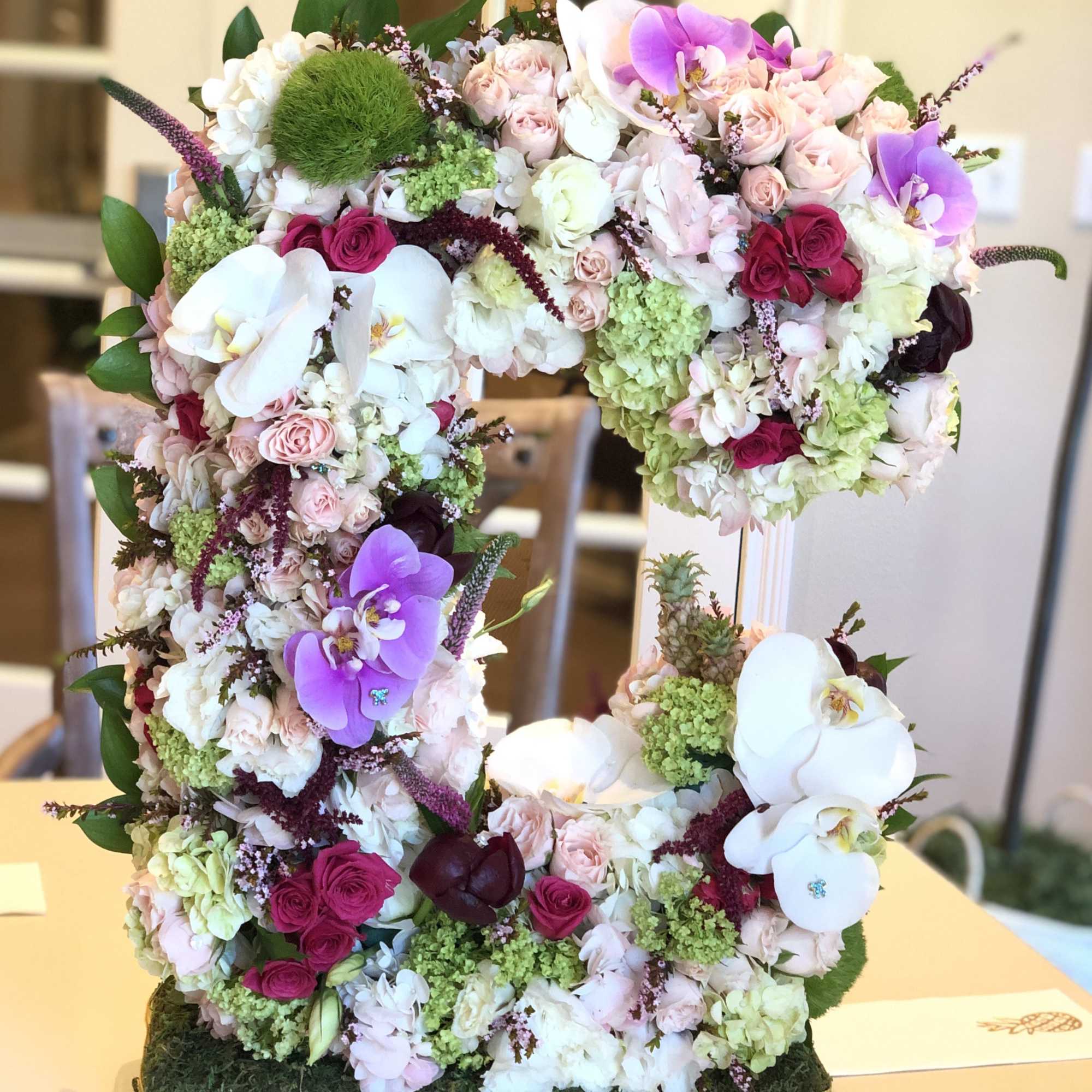 Large floral arrangement shaped like the number 5 with pink, white, and purple blooms