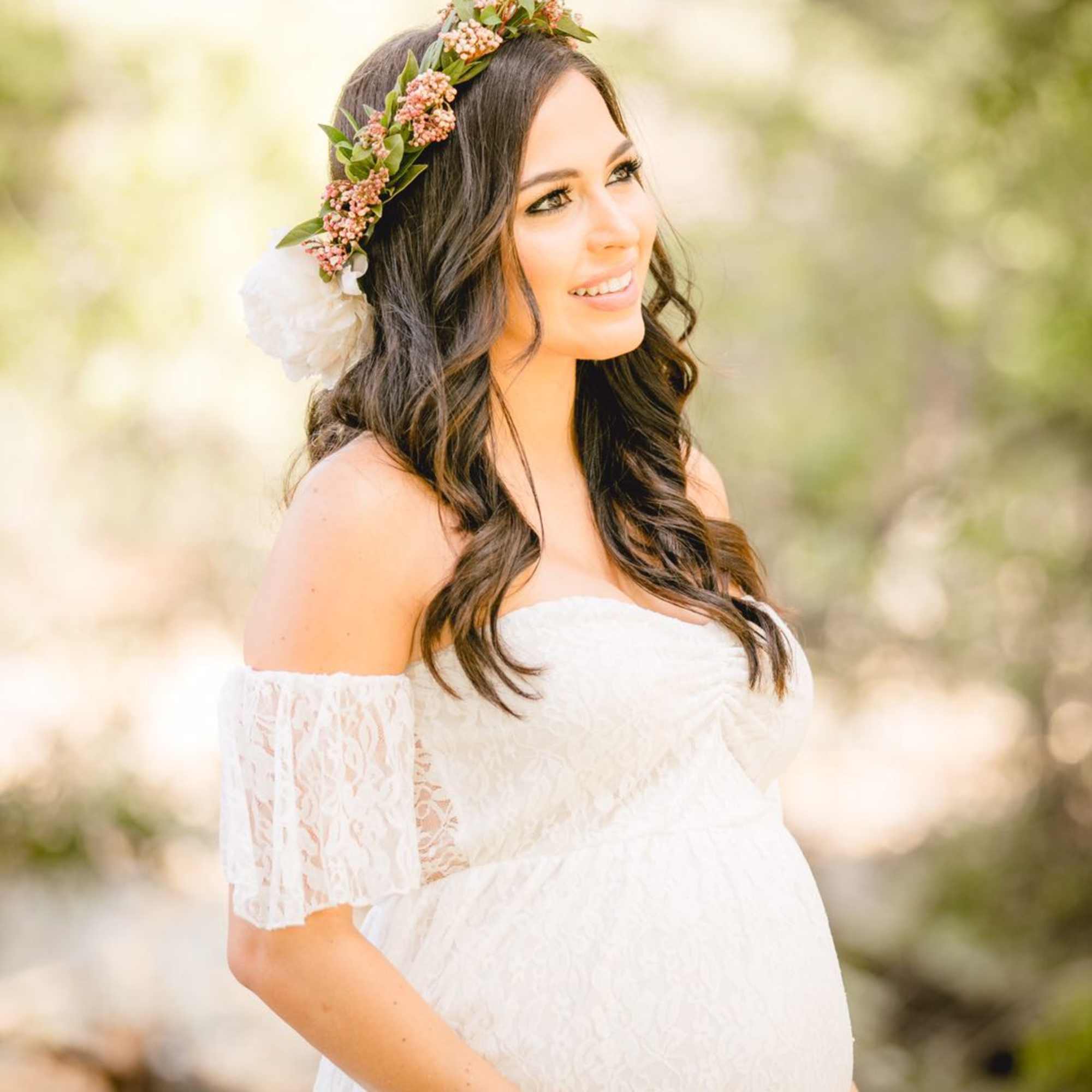 Pregnant woman in a white dress wearing a floral crown, photo 2 of 3