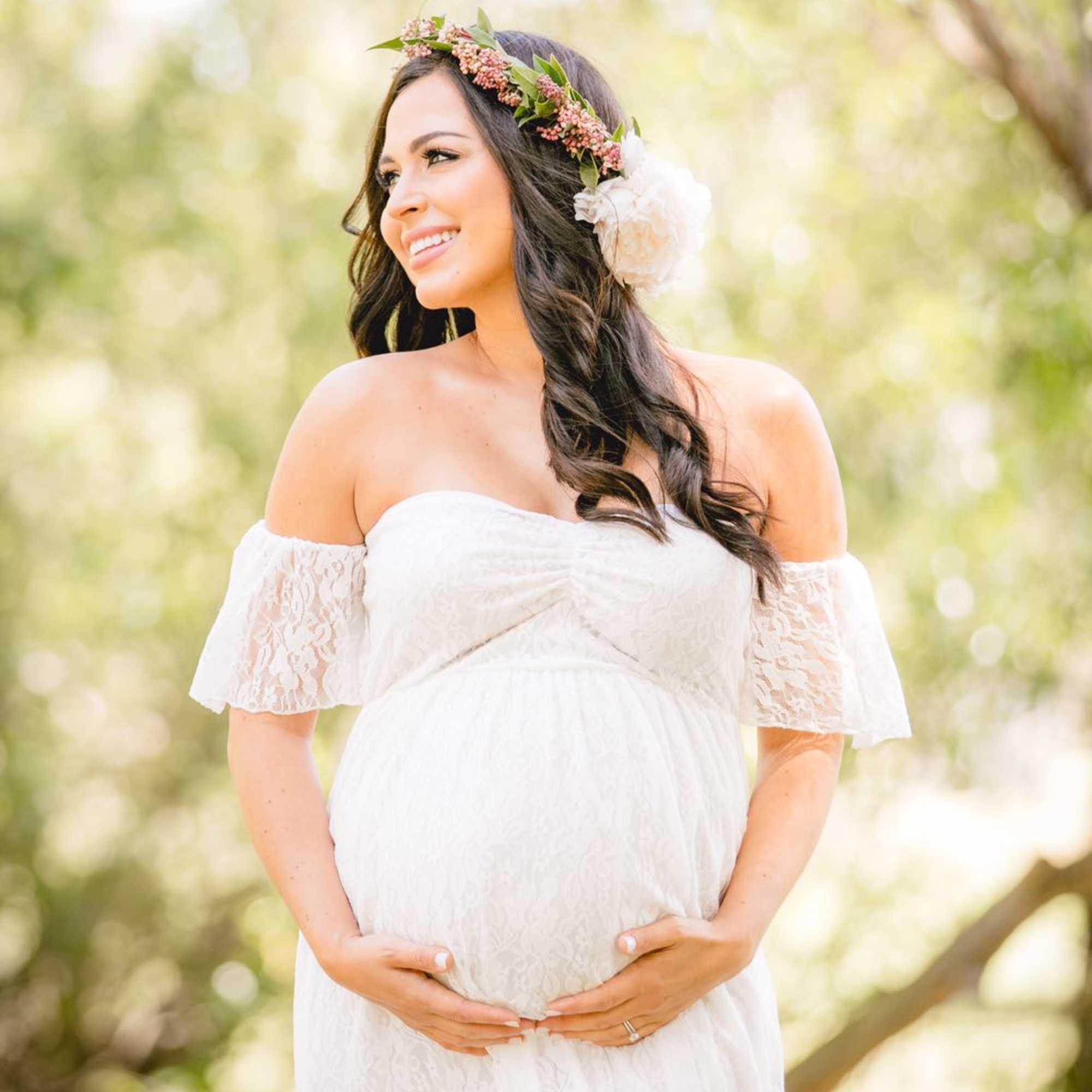 Pregnant woman in a white dress wearing a floral crown, photo 3 of 3