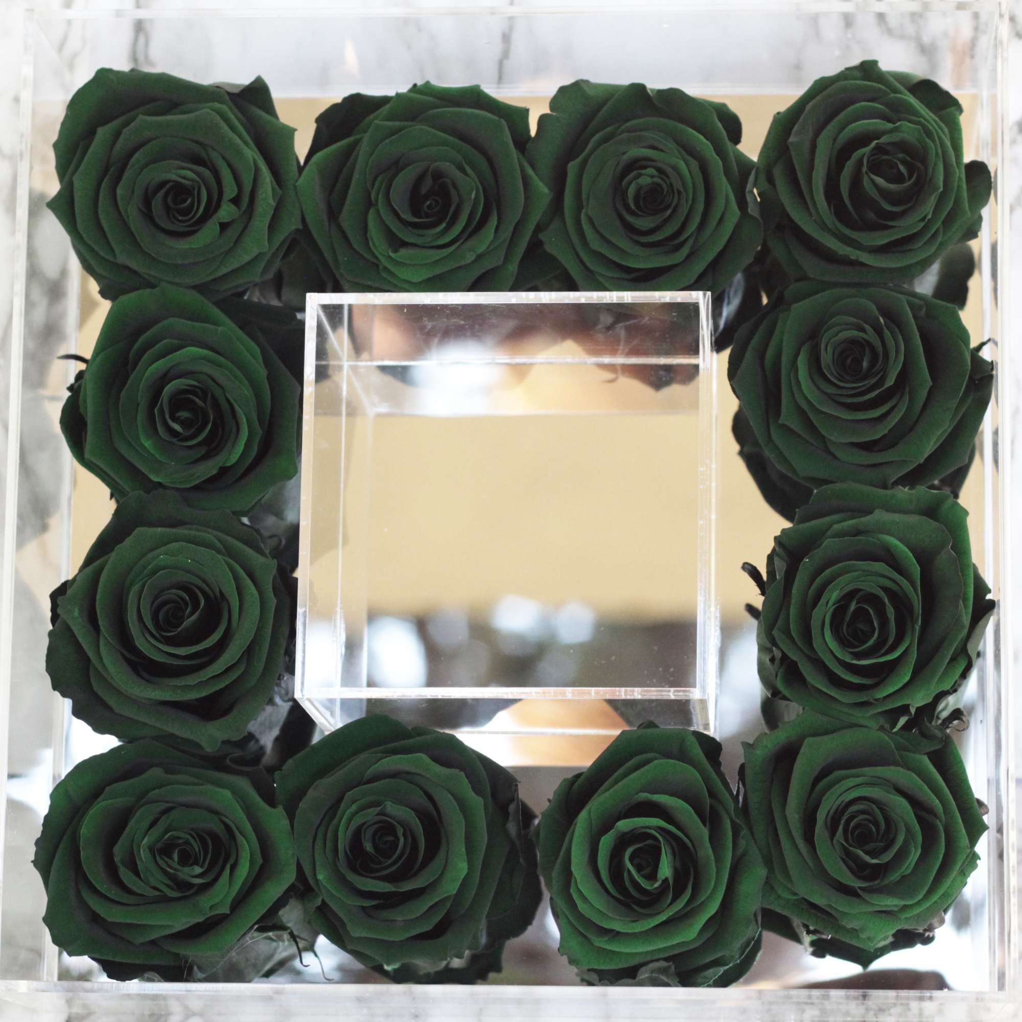 Square mirrored box with dark green roses arranged around a clear center cube