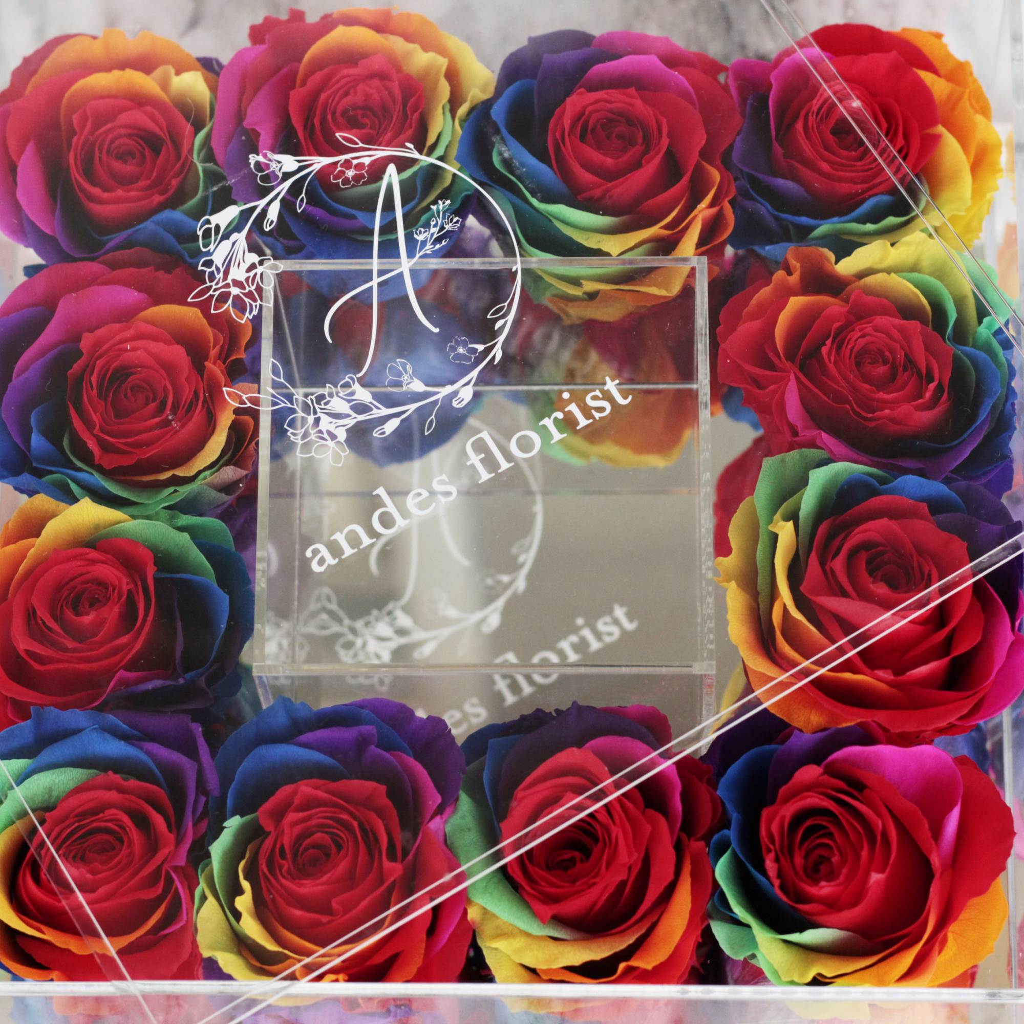 Box of rainbow-colored roses arranged around a clear center panel