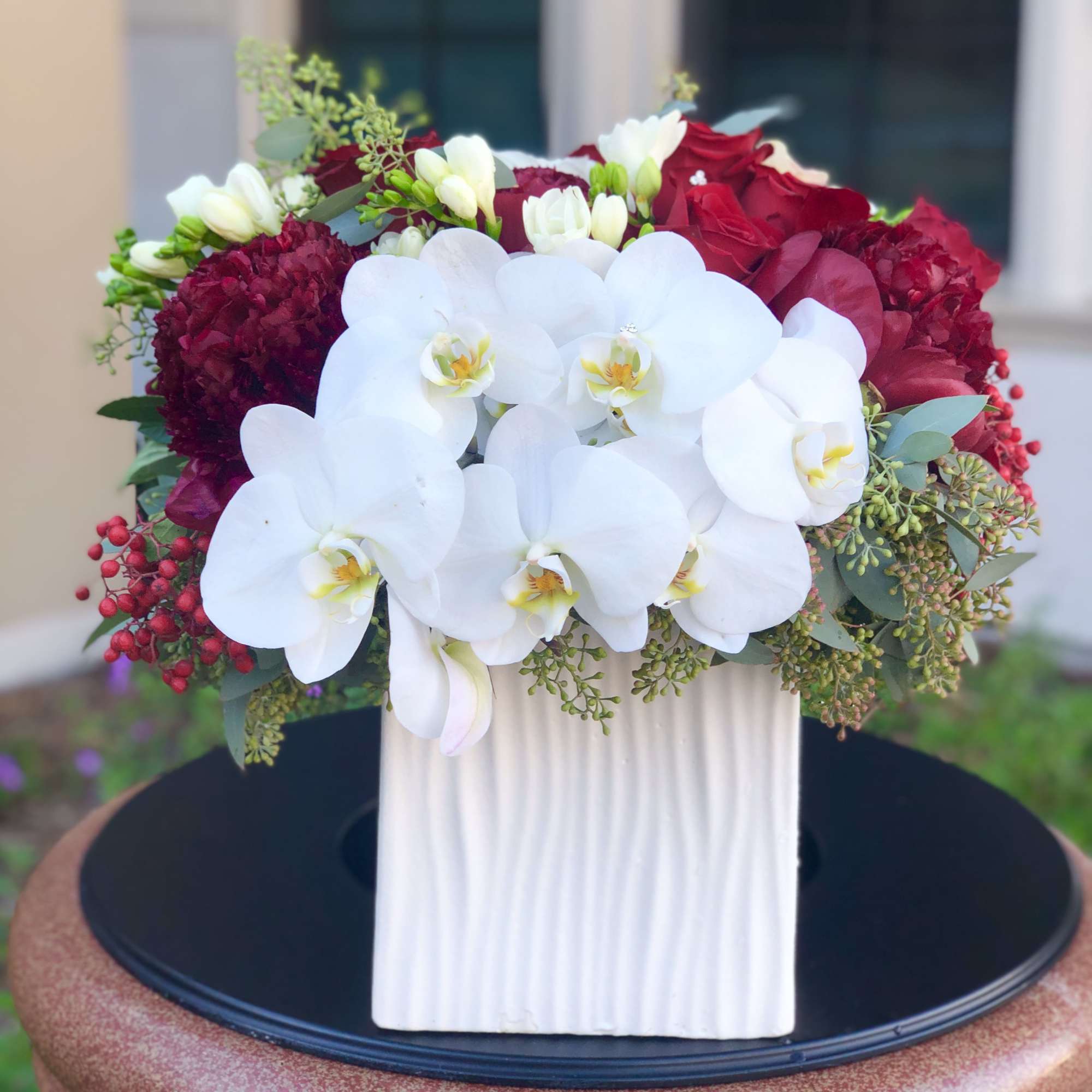 White orchids and red roses arranged in a white vase