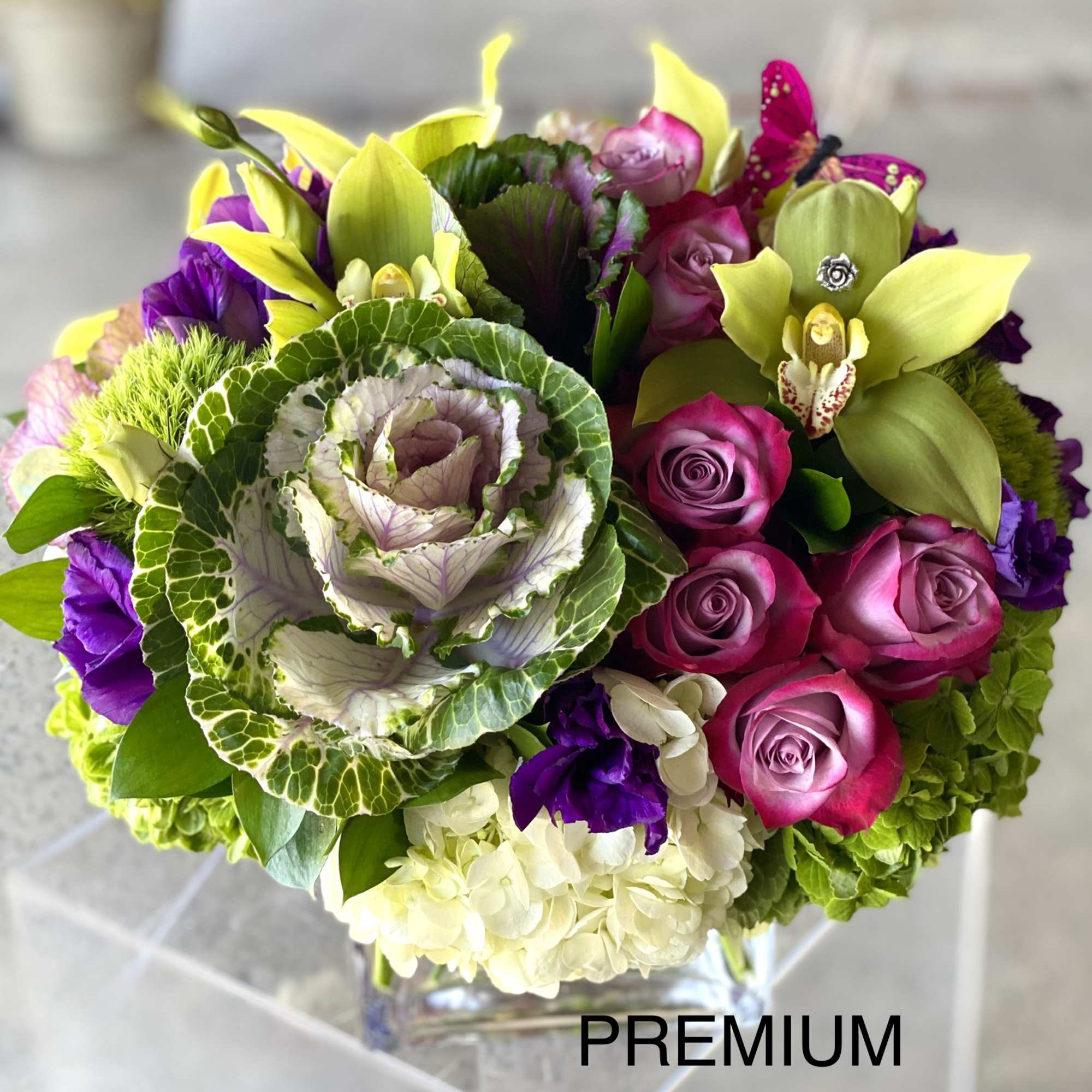 Bouquet of pink roses, green orchids, and purple flowers in a glass vase