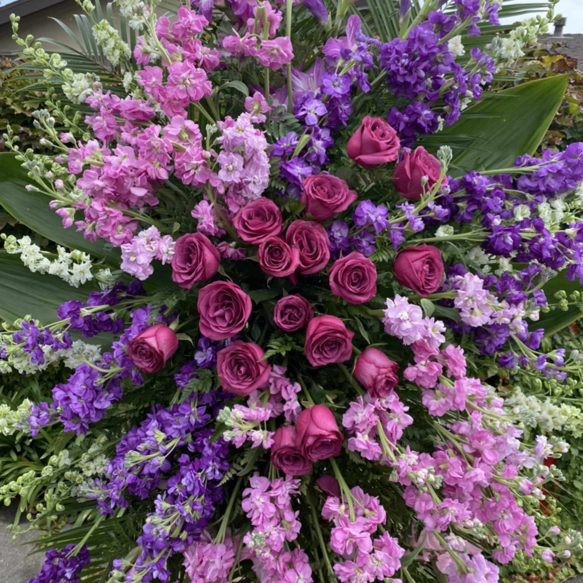 Large standing spray of pink and purple roses with mixed blossoms