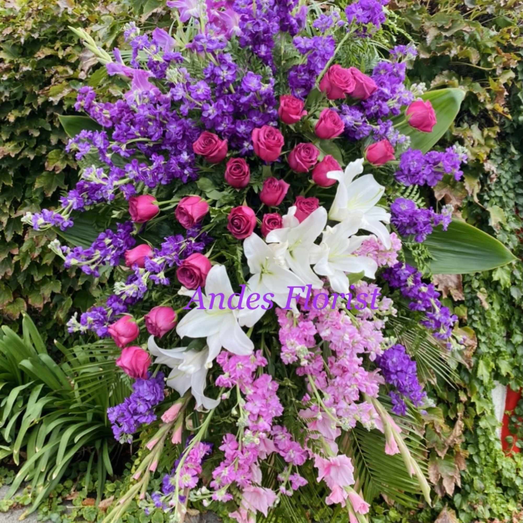 Large standing floral spray with pink roses, white lilies, and purple flowers