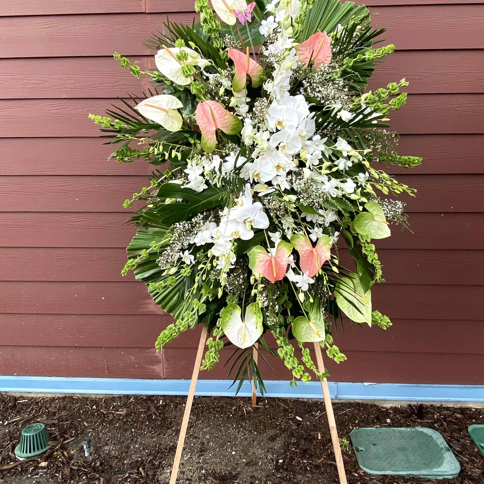 Large standing floral spray with white orchids and pink anthuriums on an easel