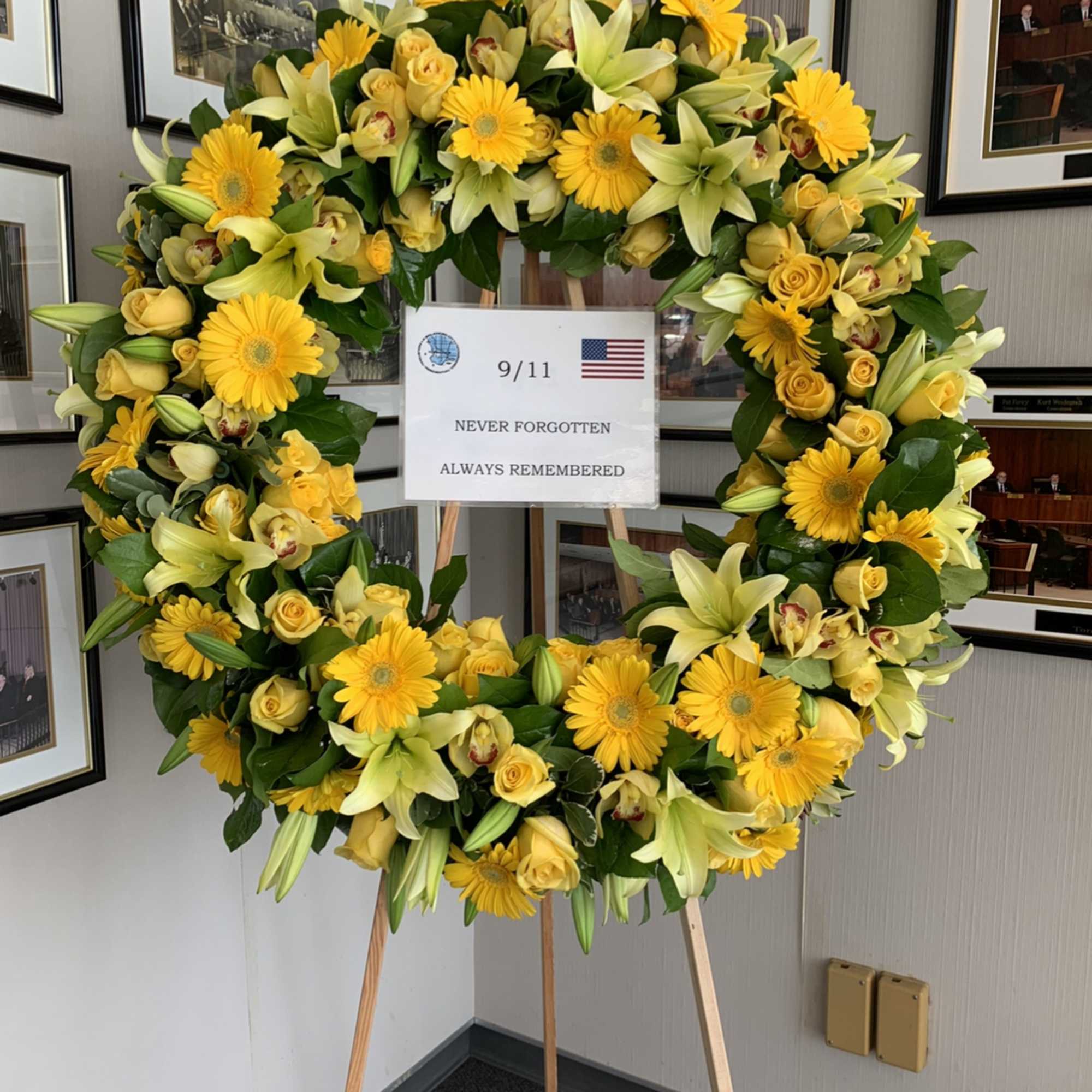 Yellow floral wreath on an easel with a 9/11 remembrance sign, photo 2 of 3