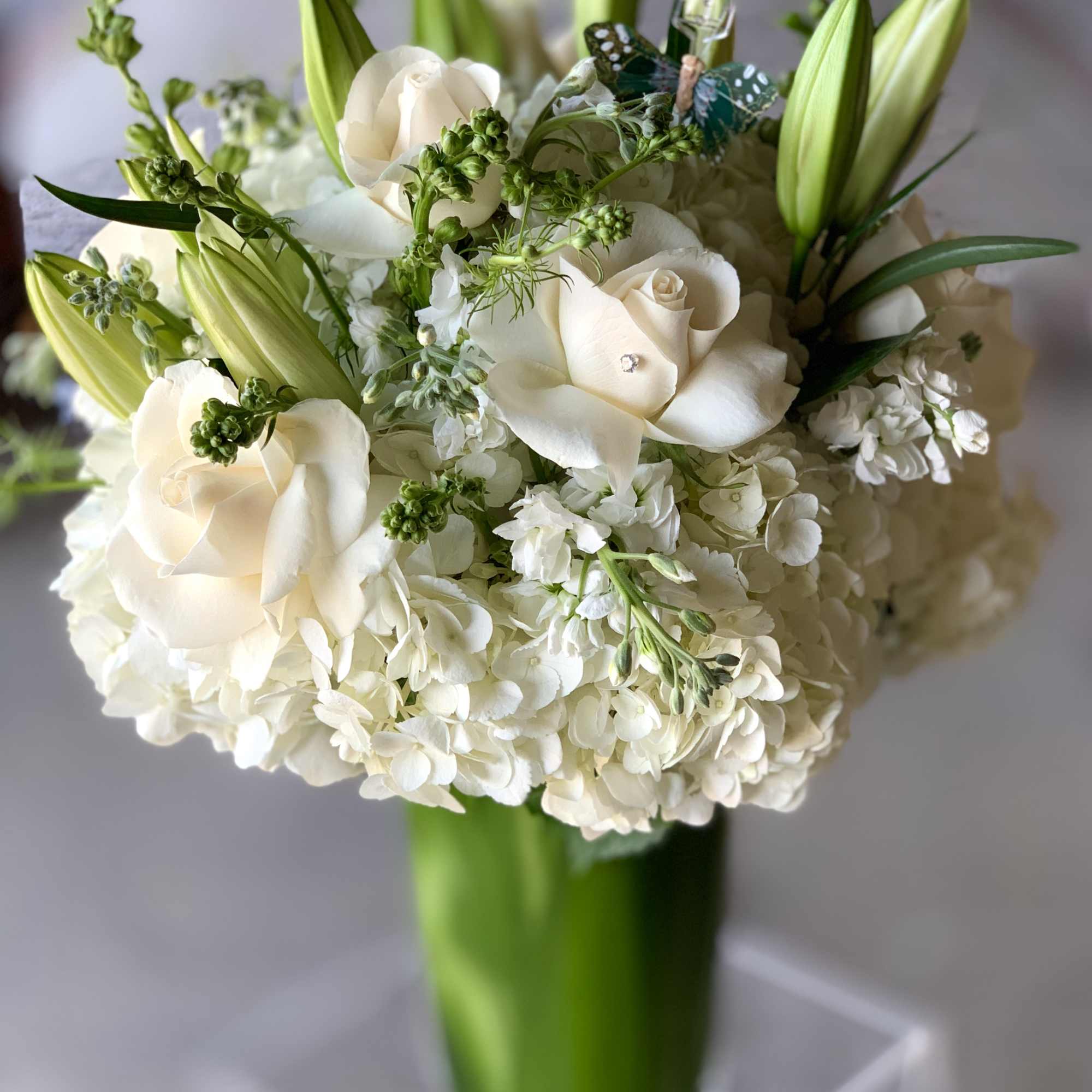 White roses and lilies arranged in a tall glass vase