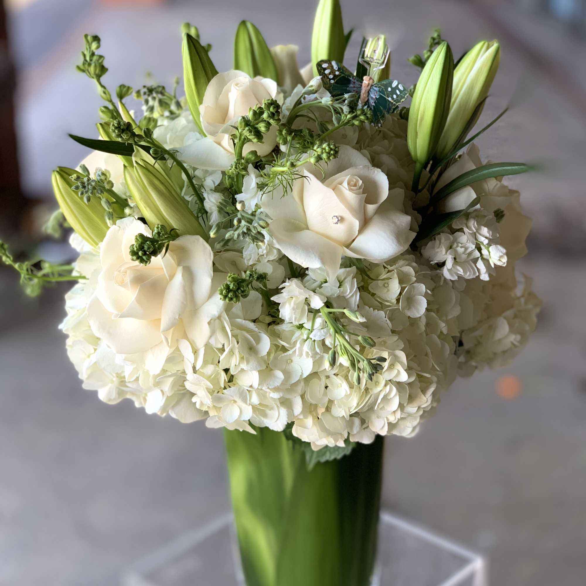 White roses and hydrangeas with green lily buds in a glass vase