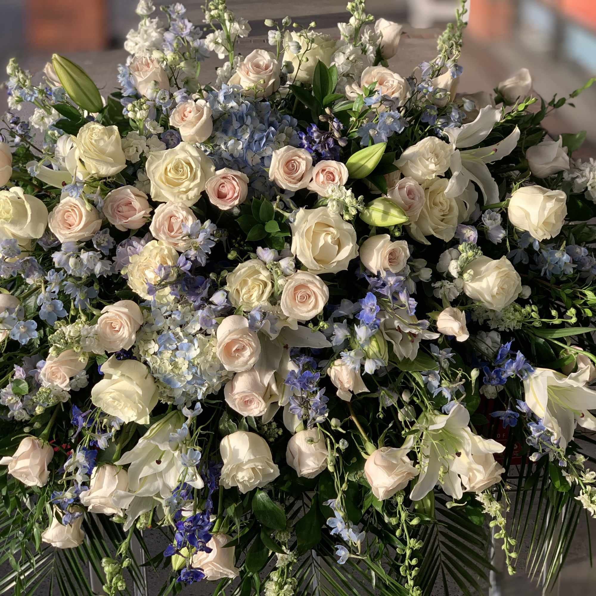 Large arrangement of pale roses and white lilies with blue flowers