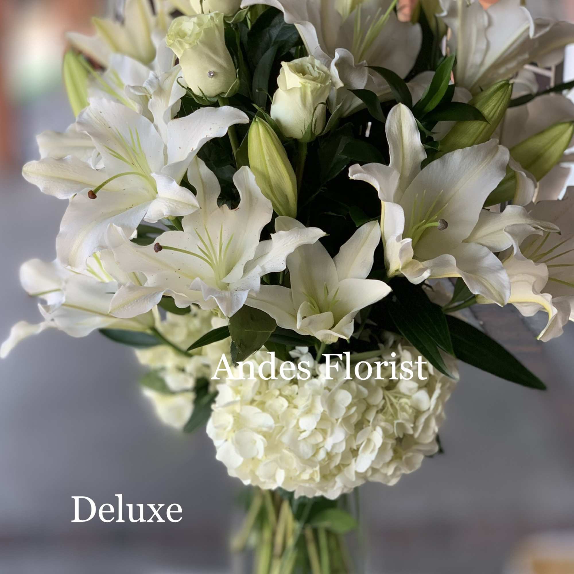 White lilies and roses arranged in a clear glass vase